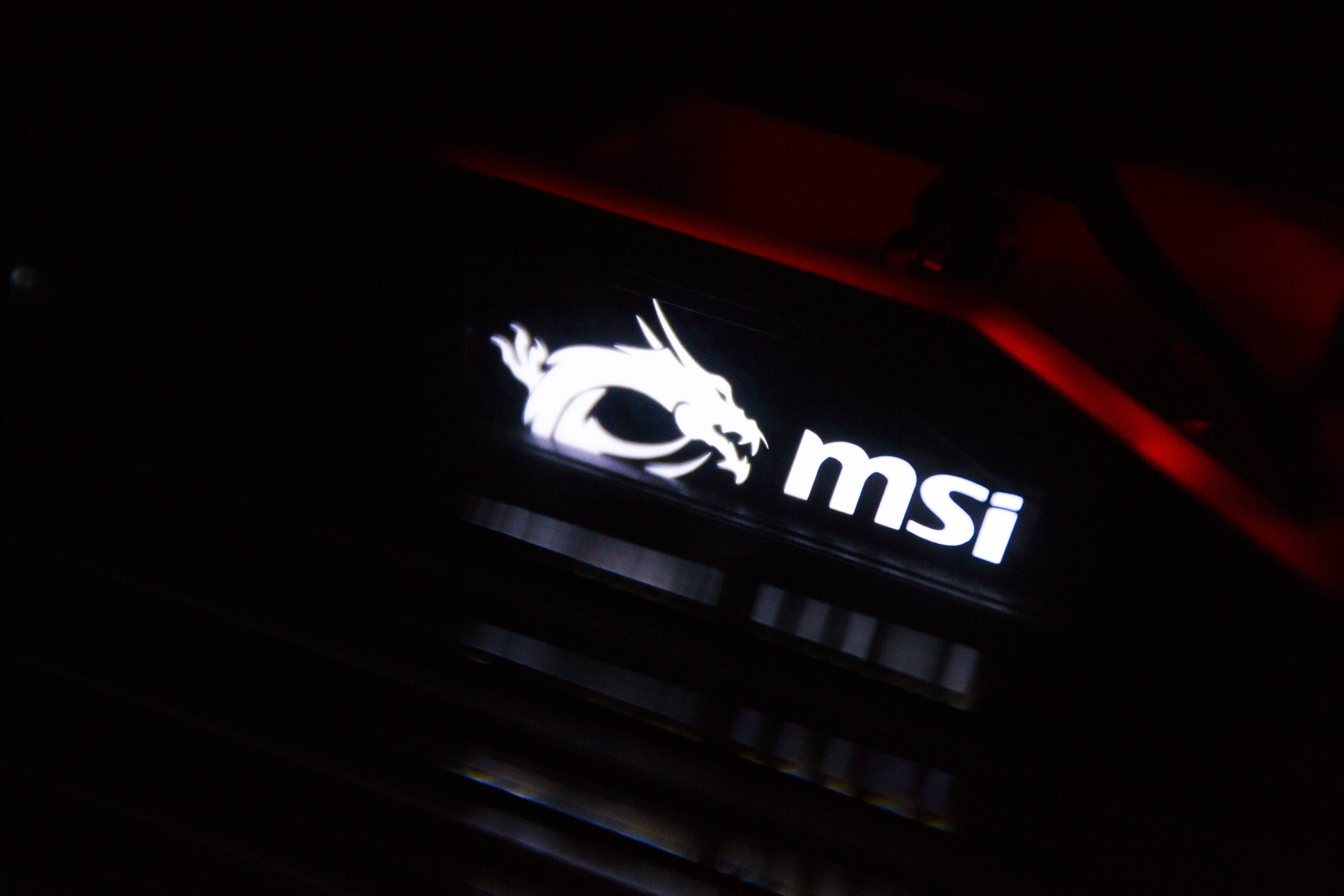MSI 4K 桌布 壁紙 — 暗色電腦機殼上帶有紅色環境燈光的發光白色MSI龍標誌和文字。