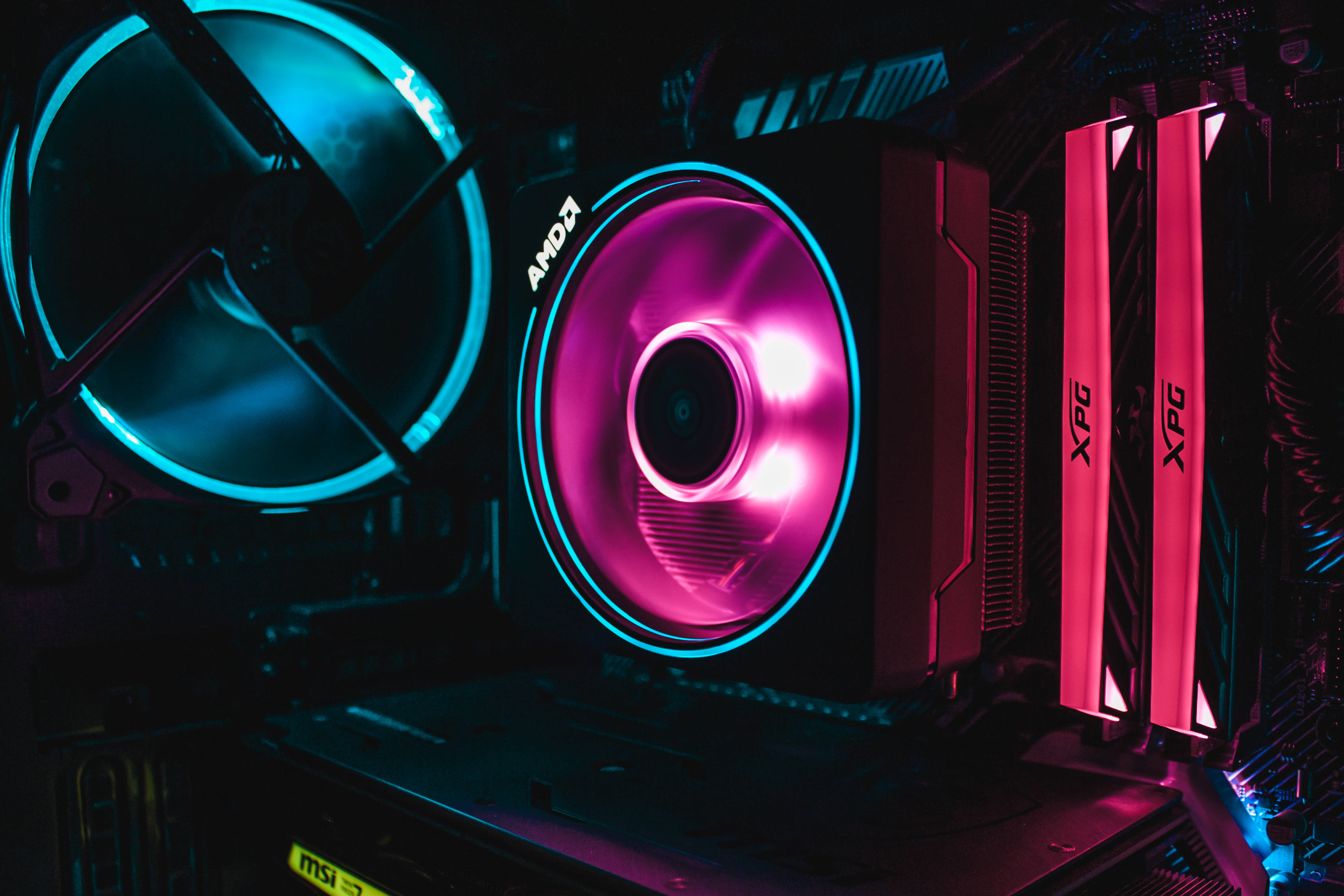 msi 2560x1080 桌布 壁紙 — 暗色電腦機箱內部，發光的RGB風扇和記憶體條特寫，帶有鮮豔的藍色和粉紅色燈光。