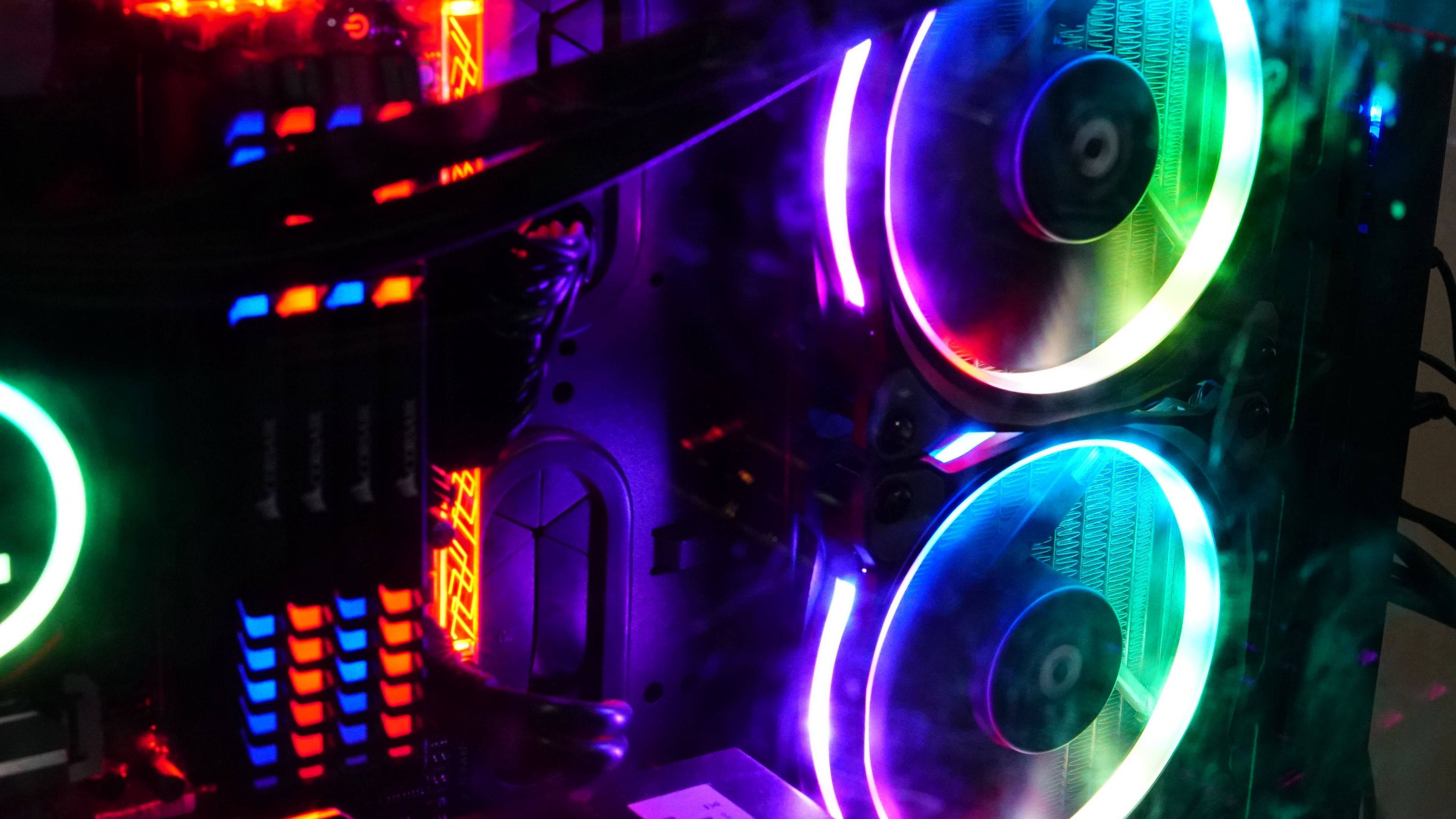 1280x720 Gaming 桌布 壁紙 — 暗黑房間中，發光電腦機殼的特寫，配備鮮豔的RGB風扇和發光組件，投射出繽紛色彩。