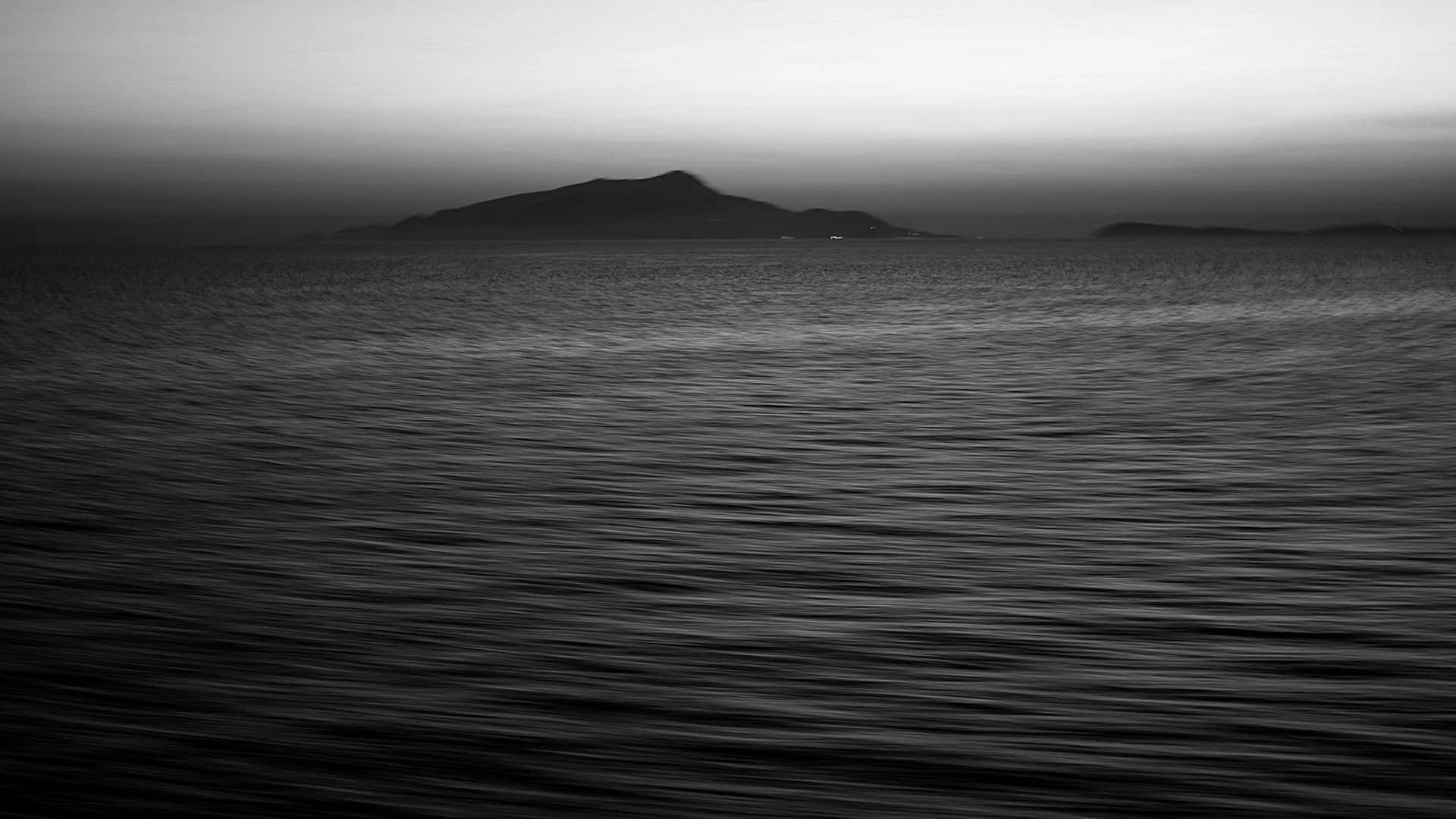 Black And White Ocean 桌布 壁紙 — 暮色下漸變天空中的單色海景，遠方有朦朧島嶼。