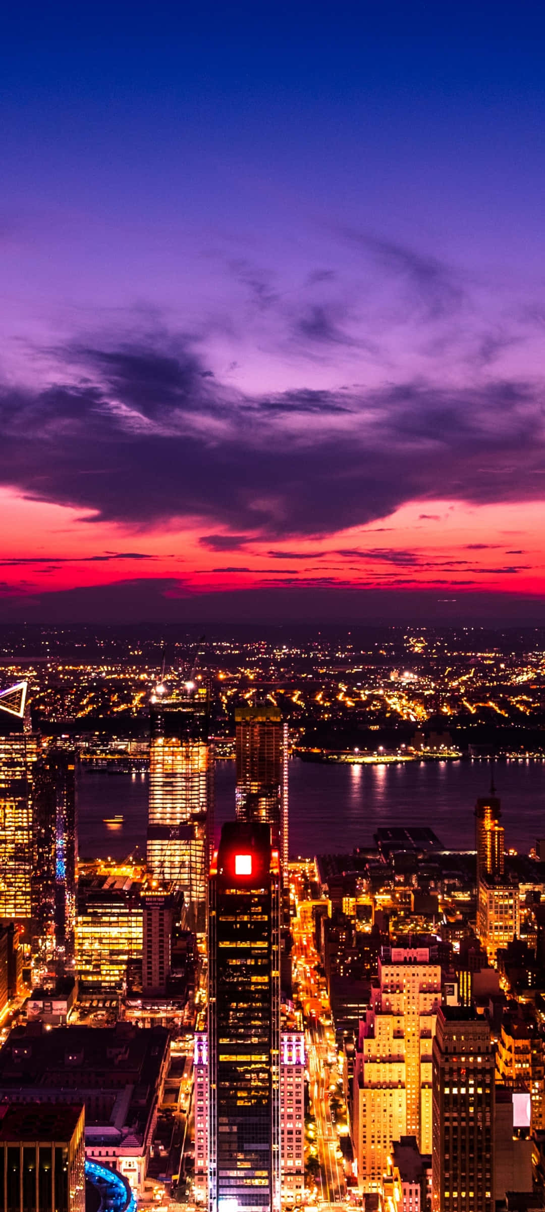City Sunset iPhone 桌布 壁紙 — 暮色中充滿活力的城市景觀，摩天大樓在火熱的紫色和粉紅色天空中閃耀。