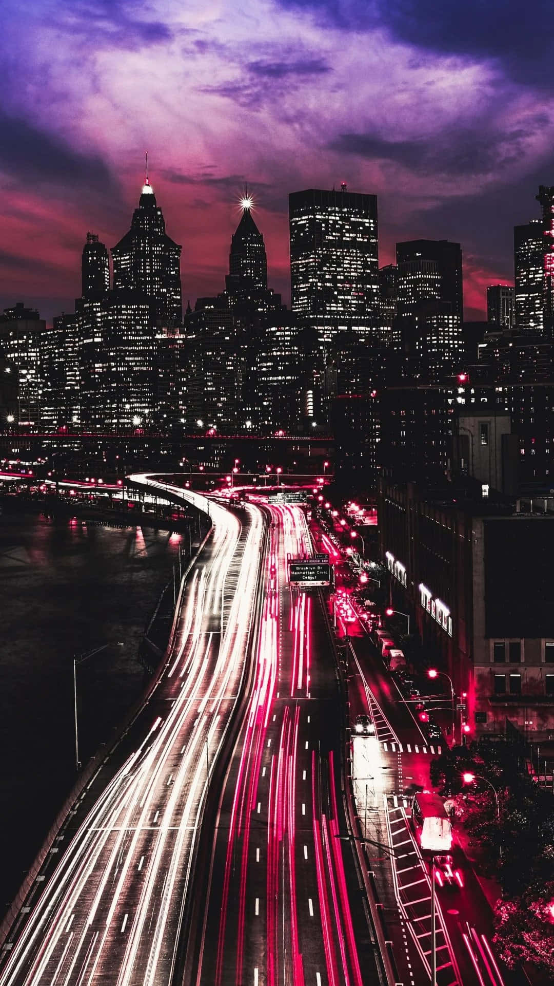 Nyc Aesthetic 桌布 壁紙 — 暮色中充滿活力的城市景觀，高聳的摩天大樓下橋樑上車流形成紅色和白色的光軌。
