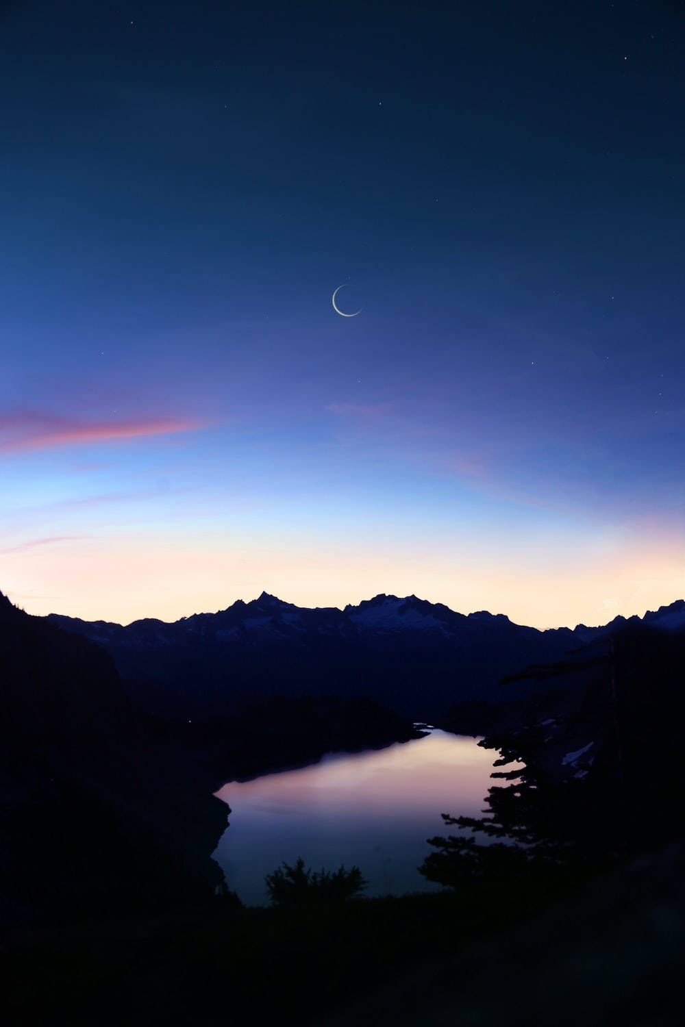 Crescent 桌布 壁紙 — 暮色中寧靜的山間湖泊，倒映著新月和星空，帶有柔和的粉紅和藍色漸變。