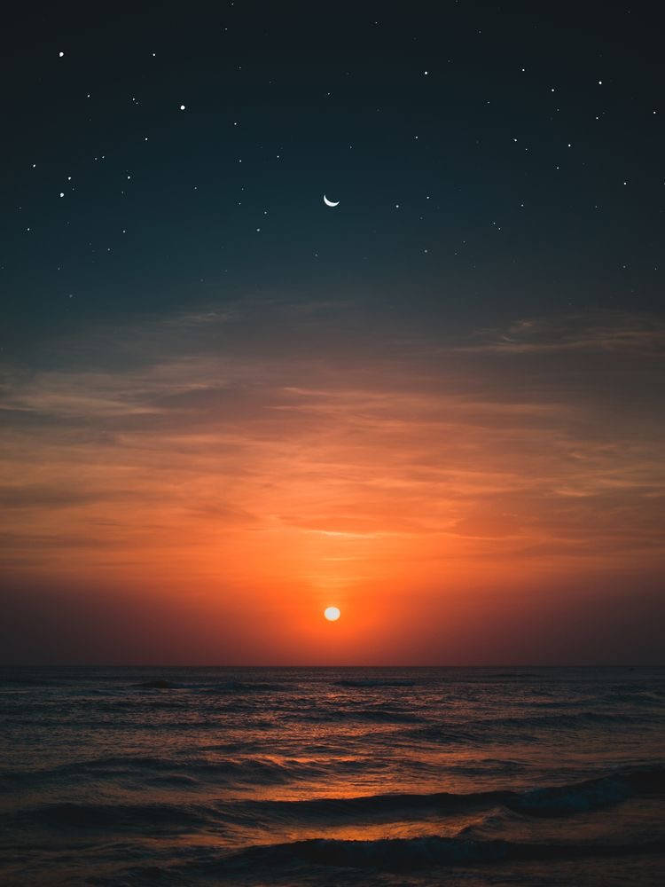 太陽與月亮 桌布 壁紙 — 暮色中寧靜的海洋，發光的太陽沉入地平線以下，新月和星星出現在漸暗的天空中。