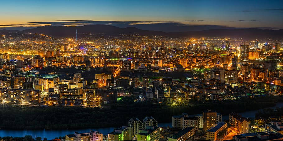 城市 桌布 壁紙 — 暮色中廣闊的城市景觀，發光的建築物和蜿蜒穿過城市範圍的河流。