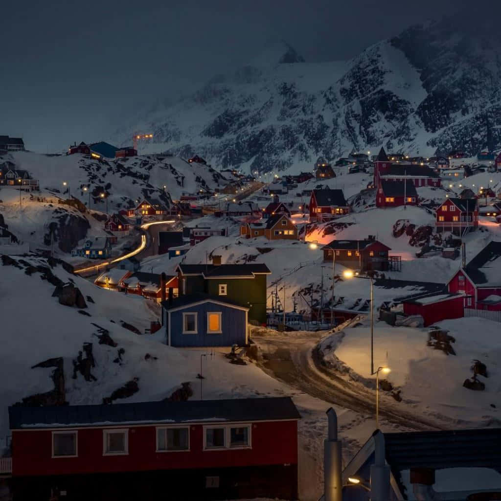Greenland 桌布 壁紙 — 暮色中群山環抱的積雪村莊，色彩繽紛的房屋透出溫暖燈光。