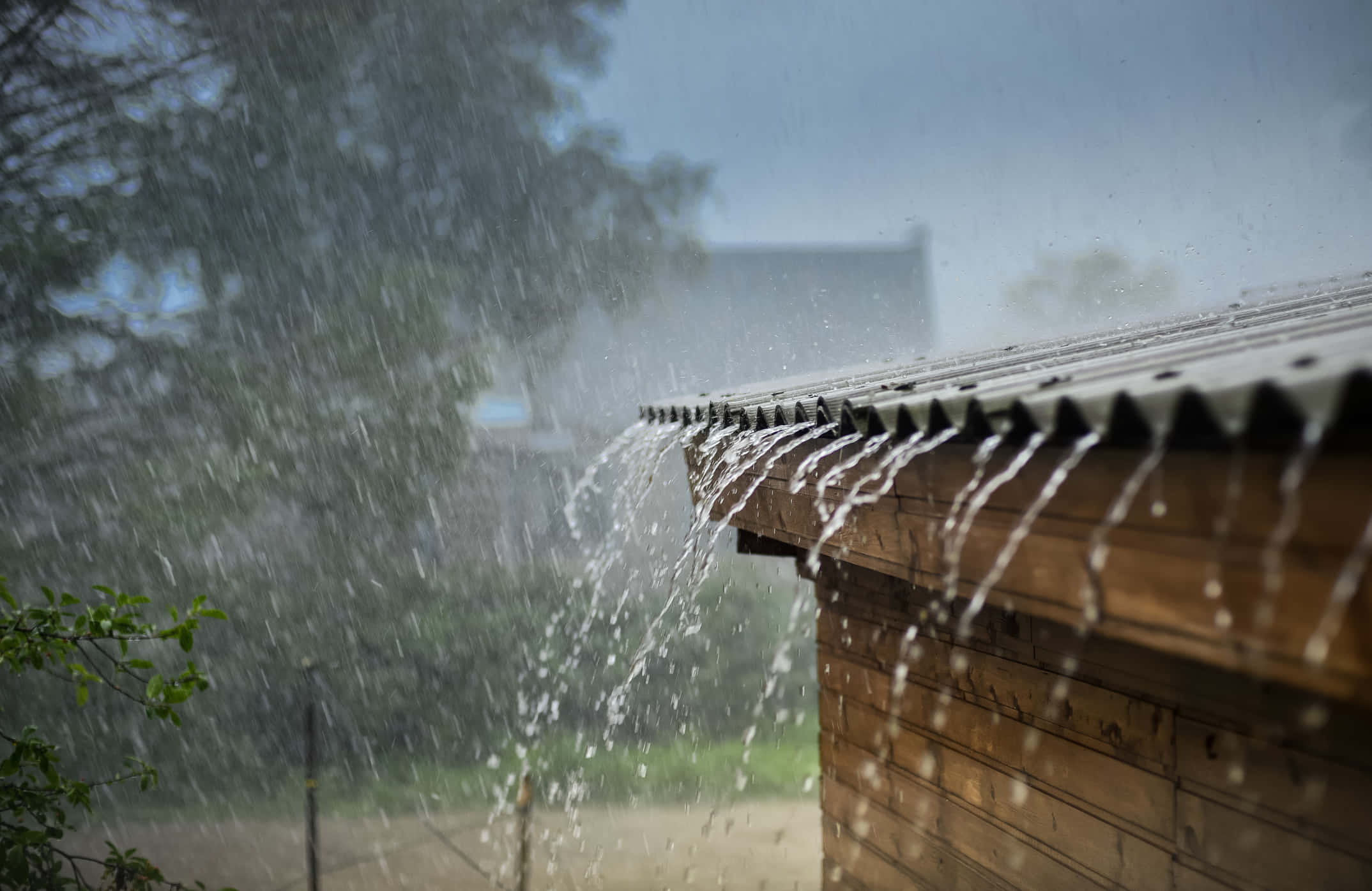 下雨 桌布 壁紙 — 暴雨從波紋鐵皮屋頂傾瀉到木造建築上，正值風暴天。