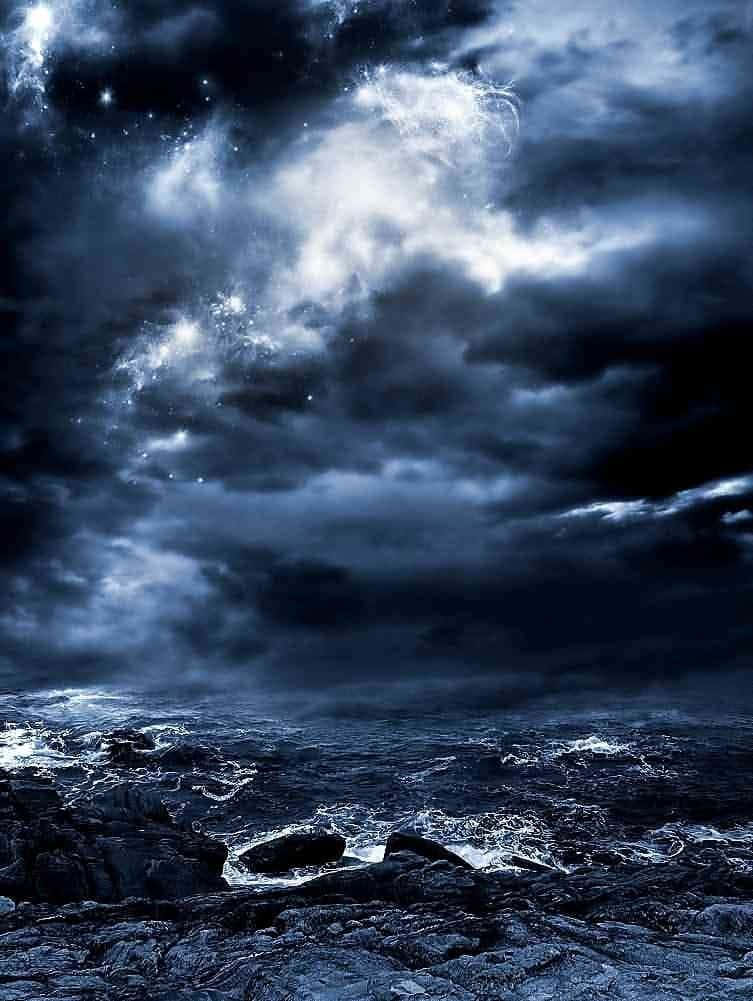 Stormy 桌布 壁紙 — 暴風雨中的海洋撞擊著崎嶇的岩石，天空陰暗，充滿旋轉的雲層和遙遠的星星。