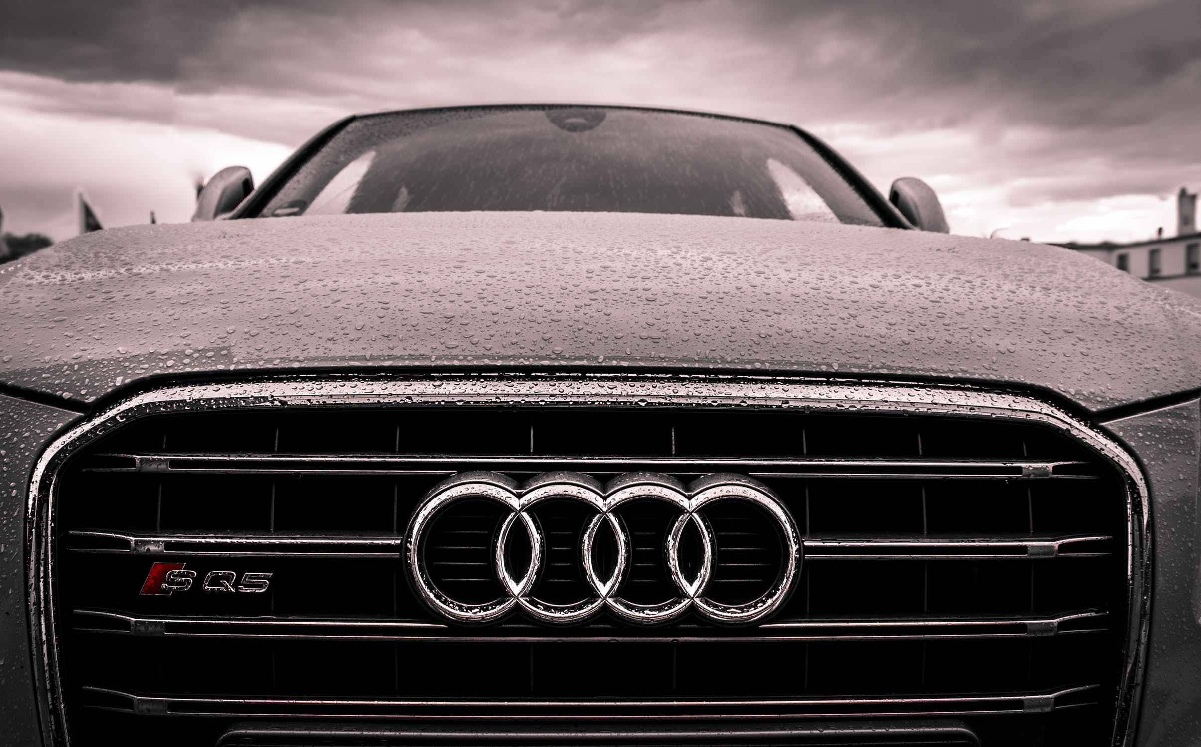 cars 桌布 壁紙 — 暴風雨天空下，濕潤的Audi SQ5水箱護罩特寫，引擎蓋上雨滴閃爍。