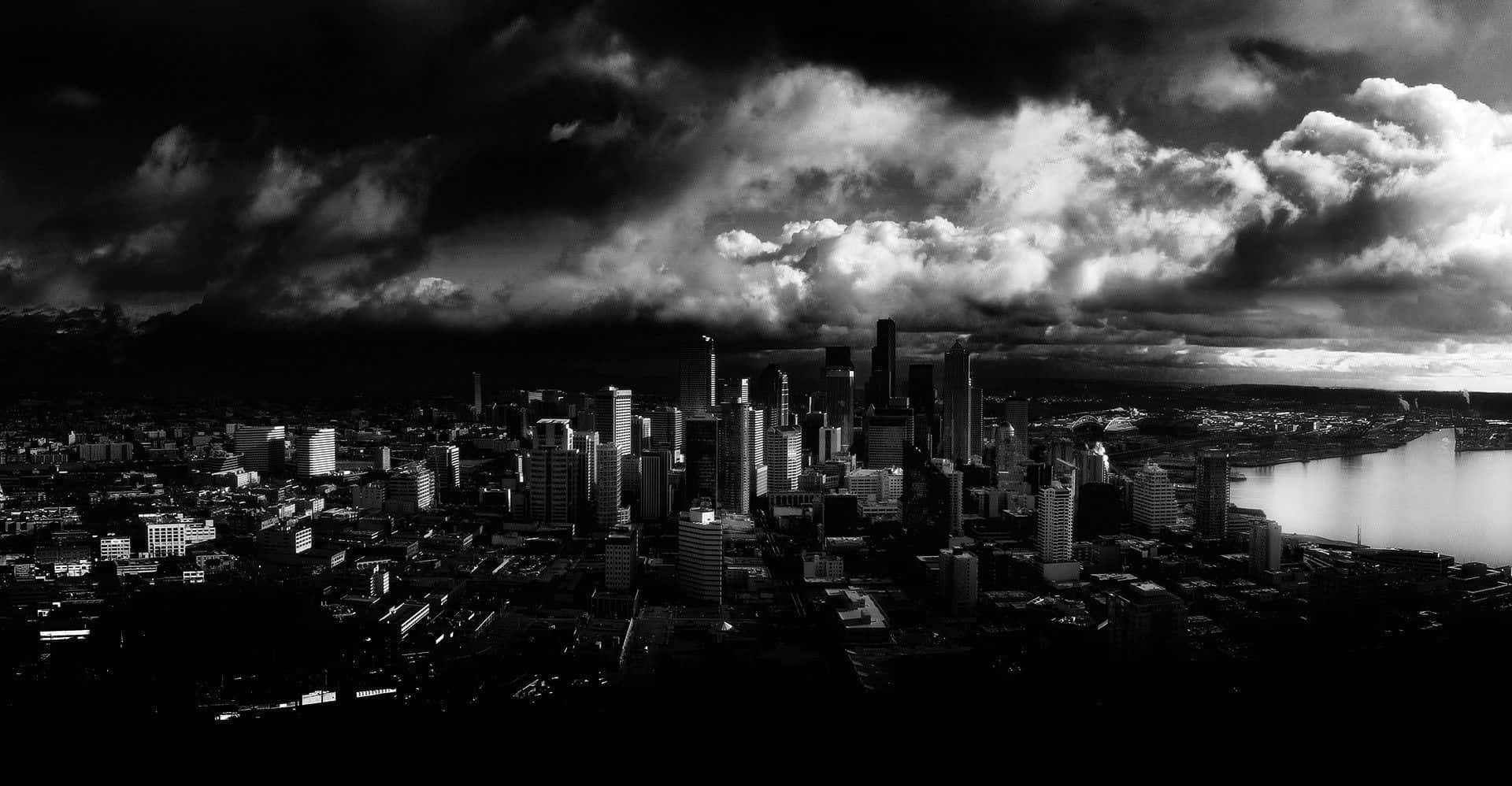 Black And White Cityscape 桌布 壁紙 — 暴風雨天空下，烏雲籠罩摩天大樓和河流的戲劇性黑白城市景觀。