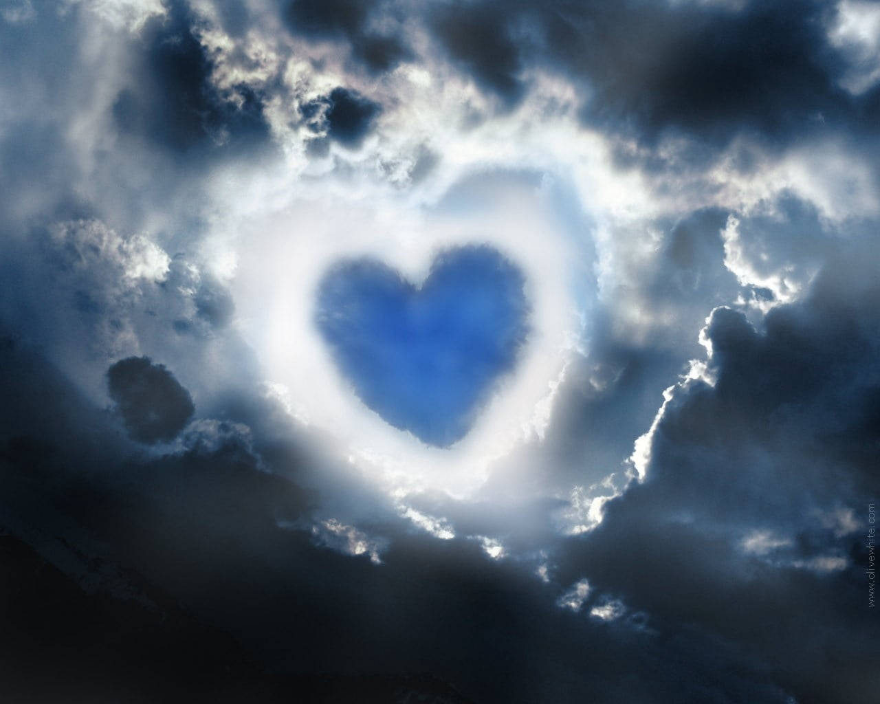 Clouds Aesthetics 桌布 壁紙 — 暴風雲中一個發光的愛心形狀開口，顯露出深藍色的天空，散發著神聖的光芒。