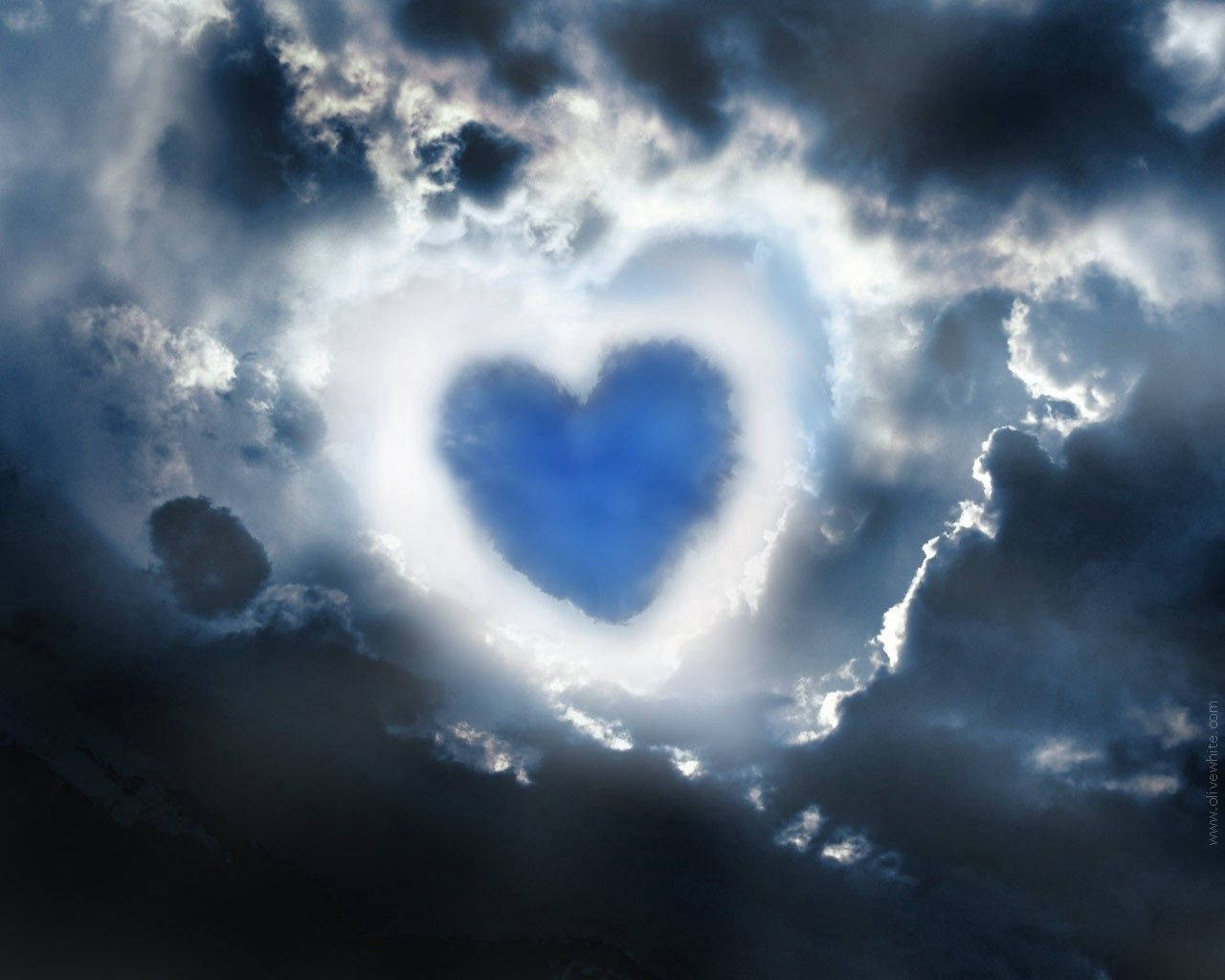 Blue Heart 桌布 壁紙 — 暴風雲中出現了一個閃爍的心形開口，露出深藍色的天空，散發著空靈的光芒。