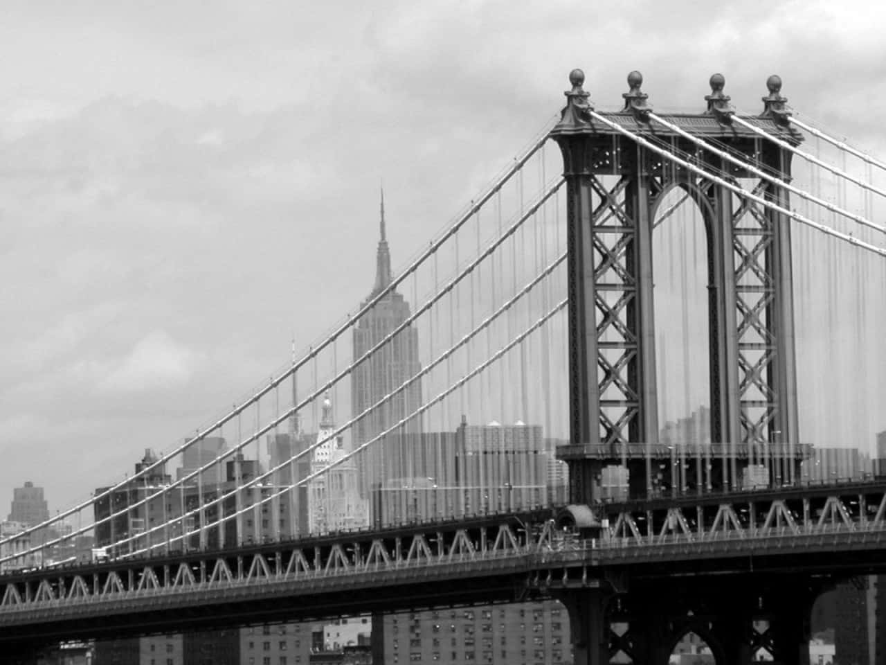Nyc 桌布 壁紙 — 曼哈頓大橋的單色景觀，帝國大廈在其鋼結構後方升起，天空多雲。