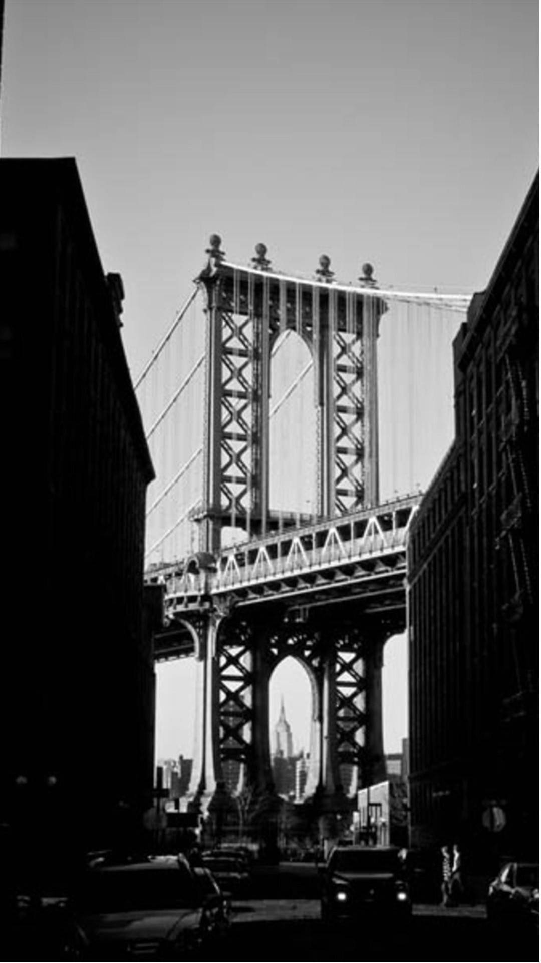 new york city iPhone x 桌布 壁紙 — 曼哈頓大橋的戲劇性黑白景觀，由高聳的城市建築和下方的街道交通框住。