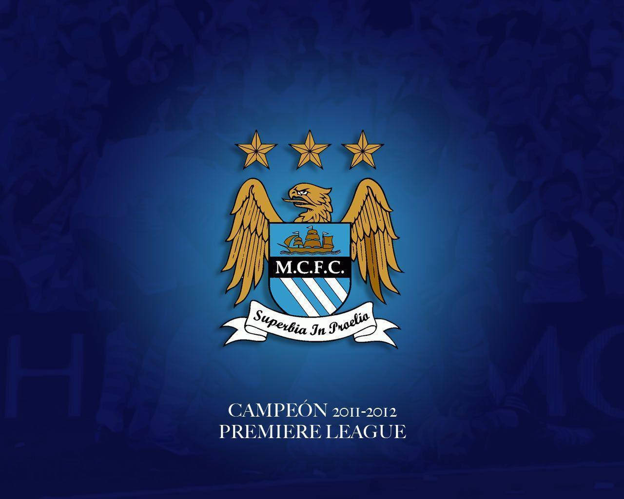 藍色 桌布 壁紙 — 曼城足球俱樂部徽章，上有三顆金星及 'Campeón 2011-2012' 字樣，背景為藍色及模糊的人群。
