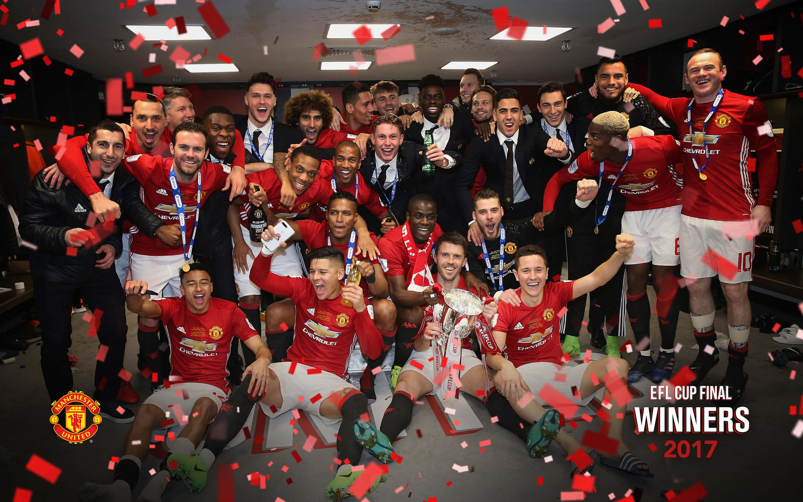 Efl Championship 桌布 壁紙 — 曼聯足球隊在更衣室慶祝英格蘭聯賽盃勝利，周圍有五彩紙屑飄落。