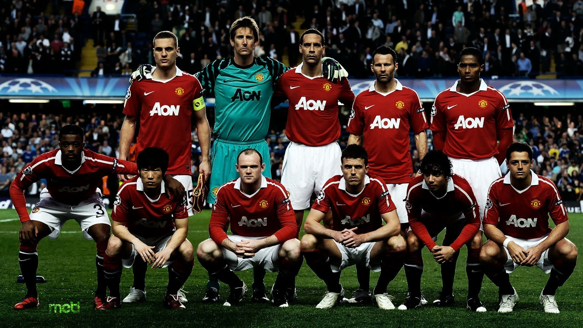 Manchester United Team 桌布 壁紙 — 曼聯足球隊身穿紅色球衣在球場草地上擺姿勢，背景有球迷。