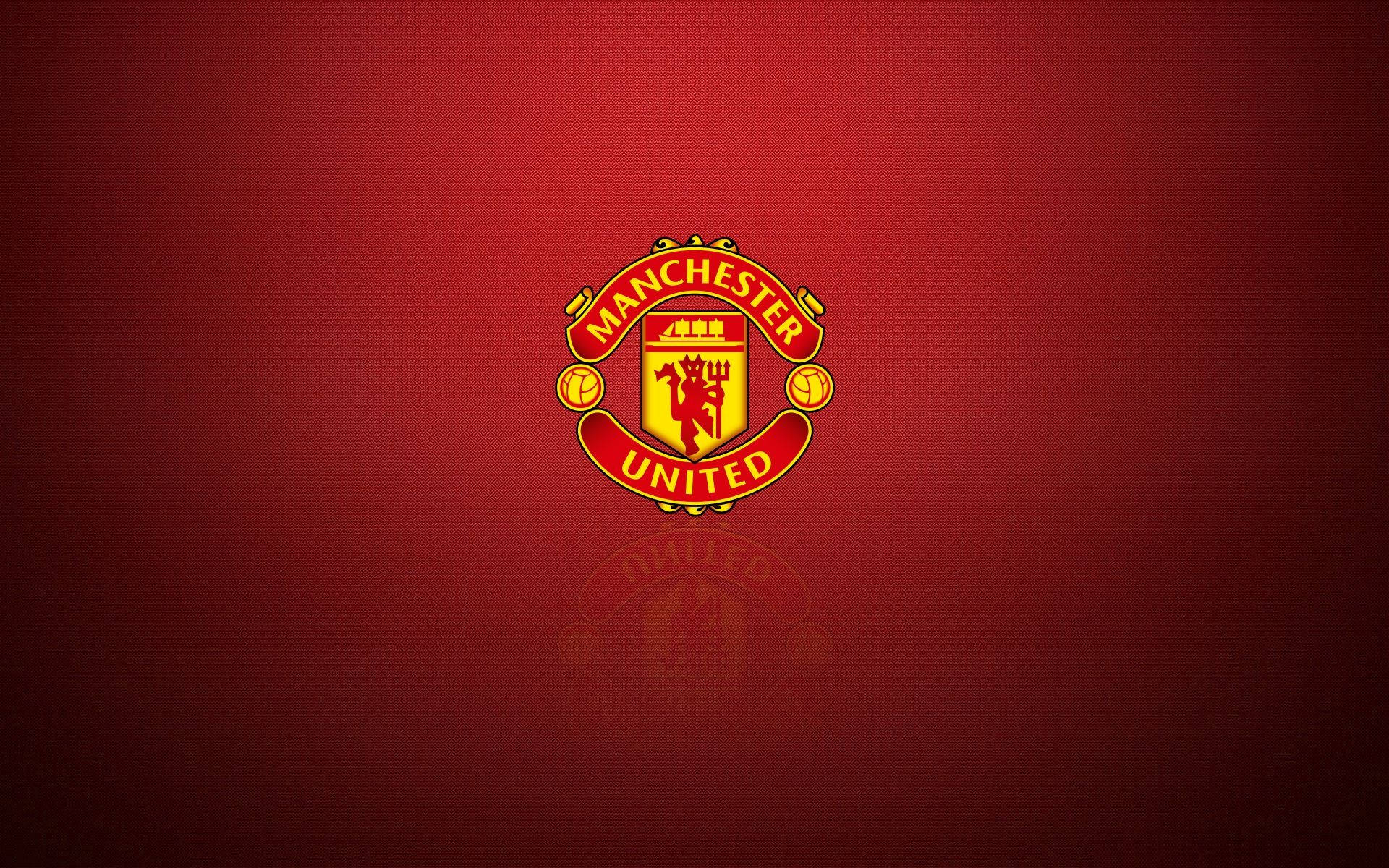 Manchester United Logo 桌布 壁紙 — 曼聯隊徽在豐富紋理的深紅背景上以鮮明的紅金色閃耀，下方帶有微妙的倒影。
