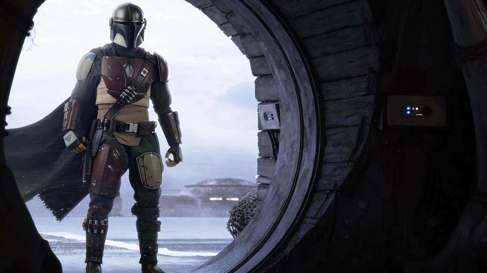 Mandalorian Pc 桌布 壁紙 — 曼達洛人站在圓形門口，俯瞰著雪景，遠處有一艘飛船，天空多雲。