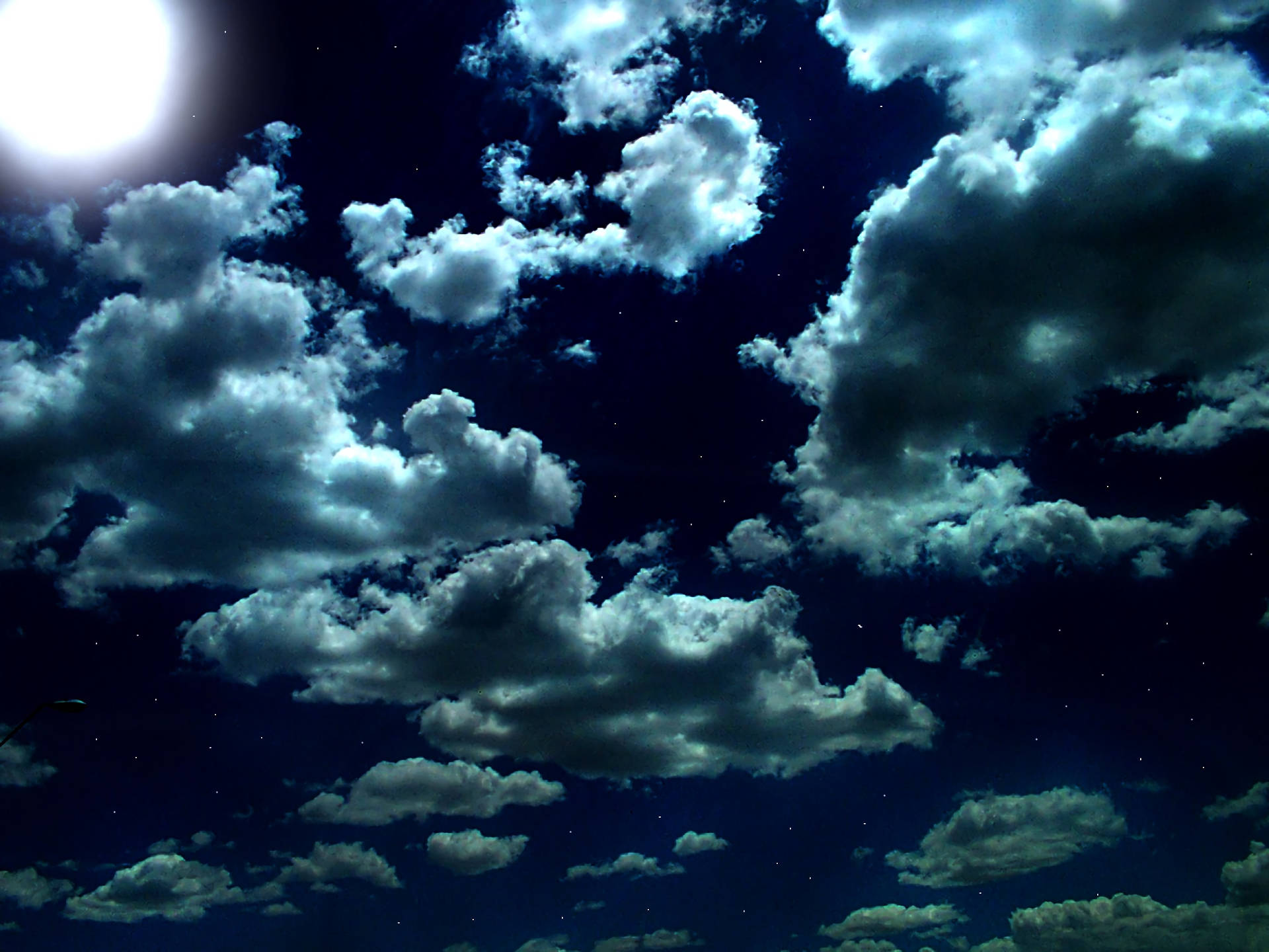 天空 桌布 壁紙 — 月光下的雲朵飄過繁星點點的夜空，散發著空靈的藍色和白色光芒。