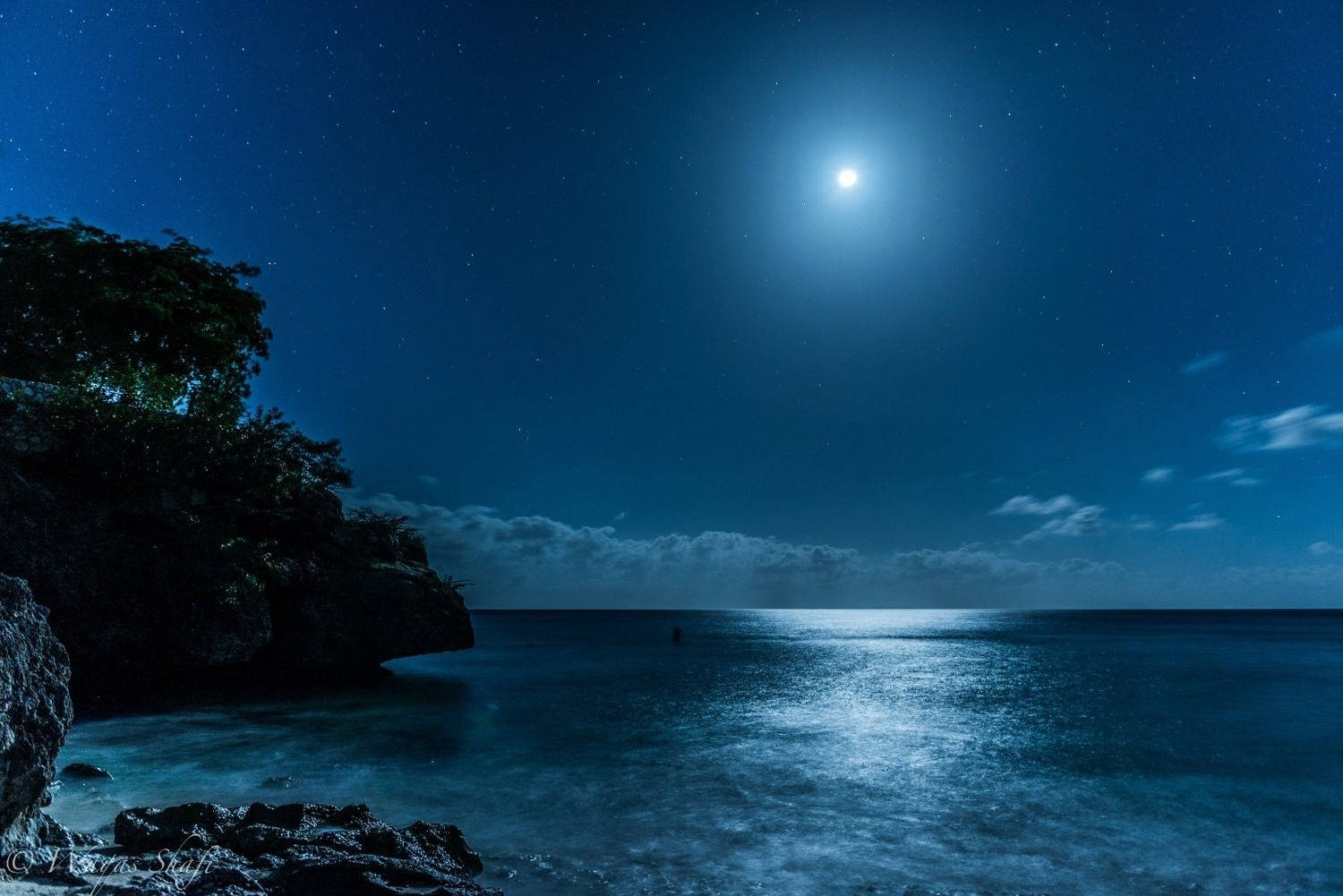 iPhone 桌布 壁紙 — 月光在平靜的海水上閃爍，星空下被黑暗的海岸懸崖環繞。