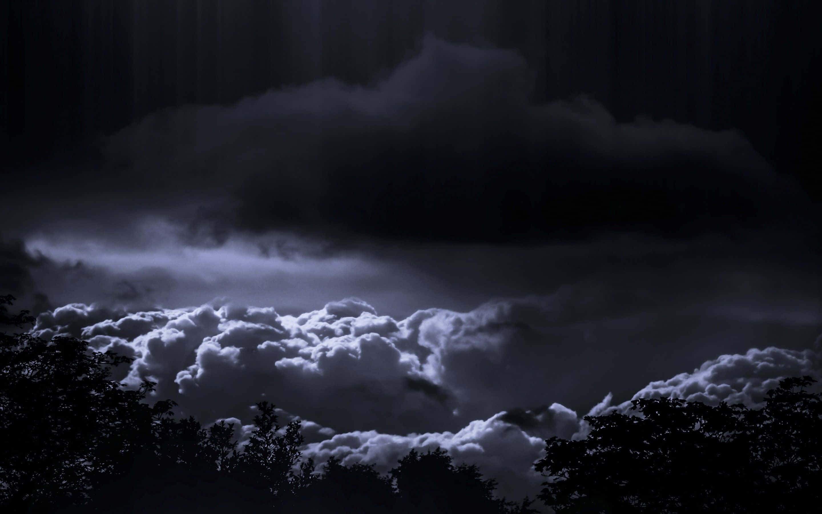 Dark Storm 桌布 壁紙 — 月光照亮了戲劇性的風暴雲層，懸浮在剪影樹梢之上，營造出憂鬱的夜空。