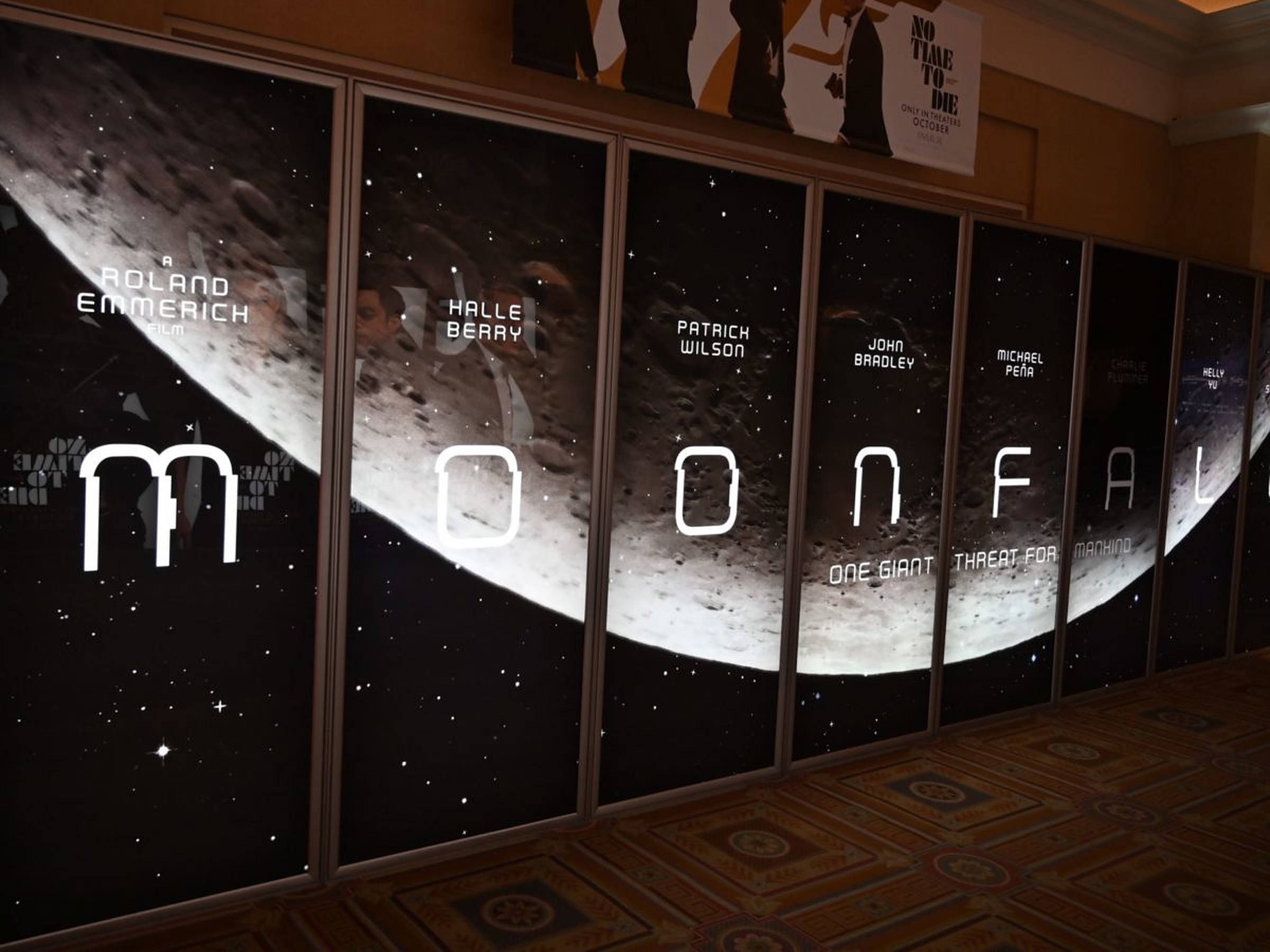 Moonfall 桌布 壁紙 — 《月球隕落》電影海報展示在牆上，帶有大型月球圖案和演員名字，背景是星空太空。
