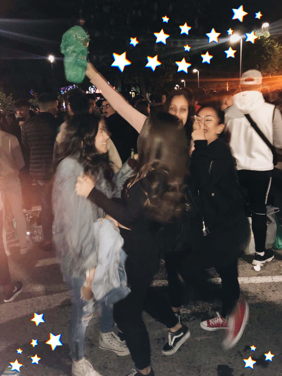 Party 桌布 壁紙 — 朋友們在夜間街頭派對中，在發光的星星濾鏡和城市燈光下大笑和擁抱。