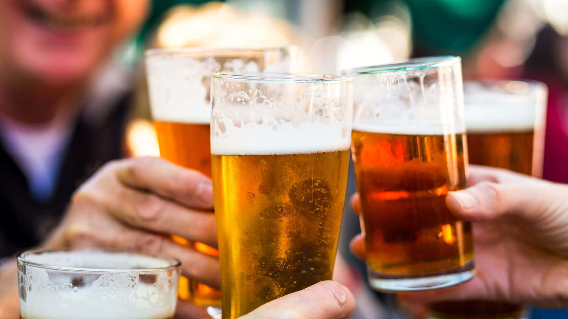 Beer 桌布 壁紙 — 朋友們在溫暖的社交祝酒中碰杯，杯中盛滿帶有泡沫的黃金啤酒。