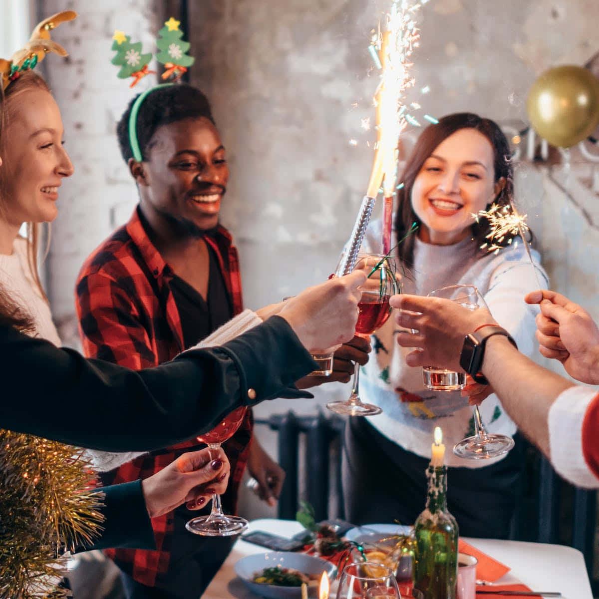 聖誕節 桌布 壁紙 — 朋友們在節日聚餐中以氣泡酒和煙火棒乾杯。