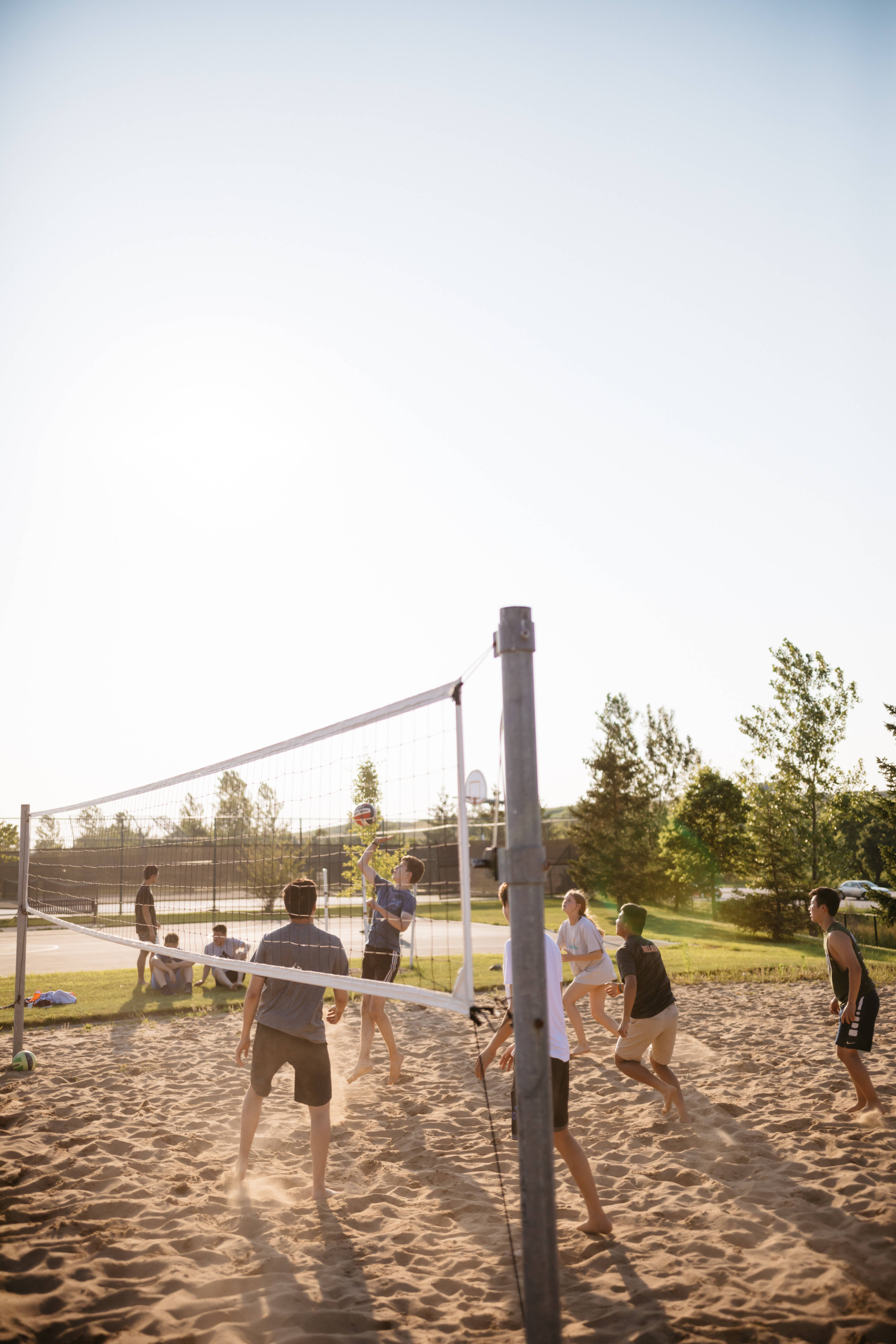 volleyball 4K 桌布 壁紙 — 朋友們在金色夕陽下打沙灘排球，沙地上投下長長的影子。