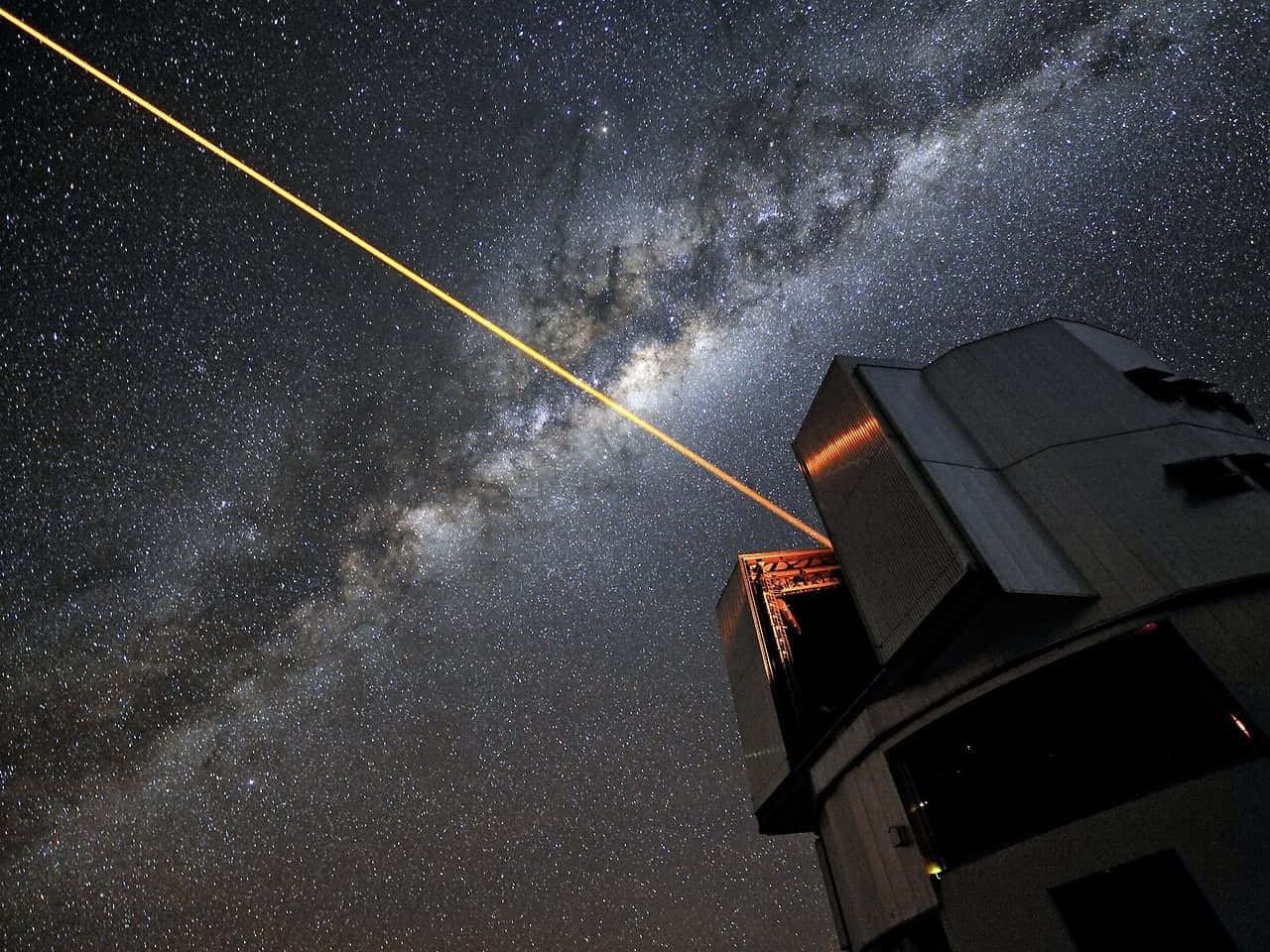 銀河 桌布 壁紙 — 望遠鏡在佈滿銀河發光塵埃帶的星空夜空中發射出一道明亮的黃色雷射光束。