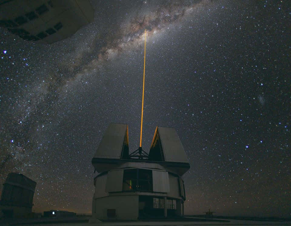 Galactic Center 桌布 壁紙 — 望遠鏡天文台在繁星點點的夜空下，向銀河系發射一道明亮的雷射。