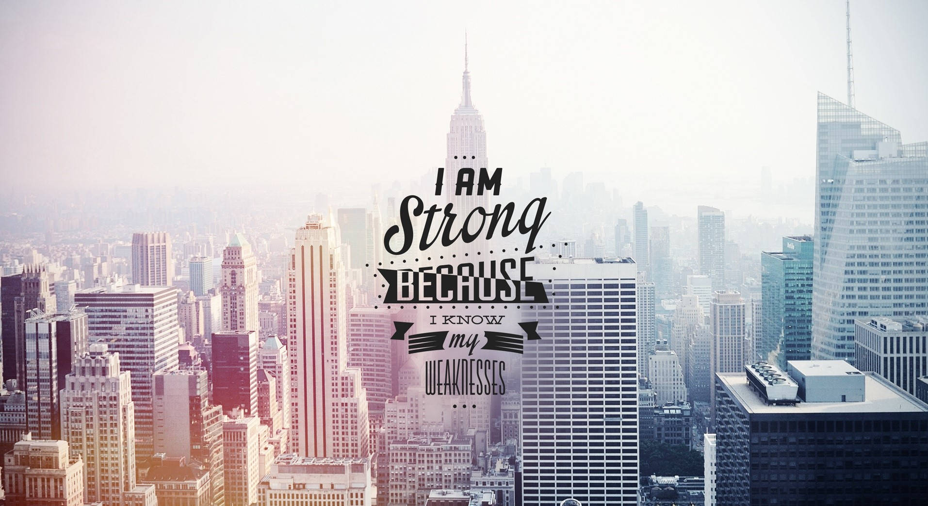 Motivational Aesthetic Desktop 桌布 壁紙 — 朦朧的城市景觀，摩天大樓沐浴在溫暖的日出光中，展示了勵志文字「我之所以堅強，是因為我知道自己的弱點」。