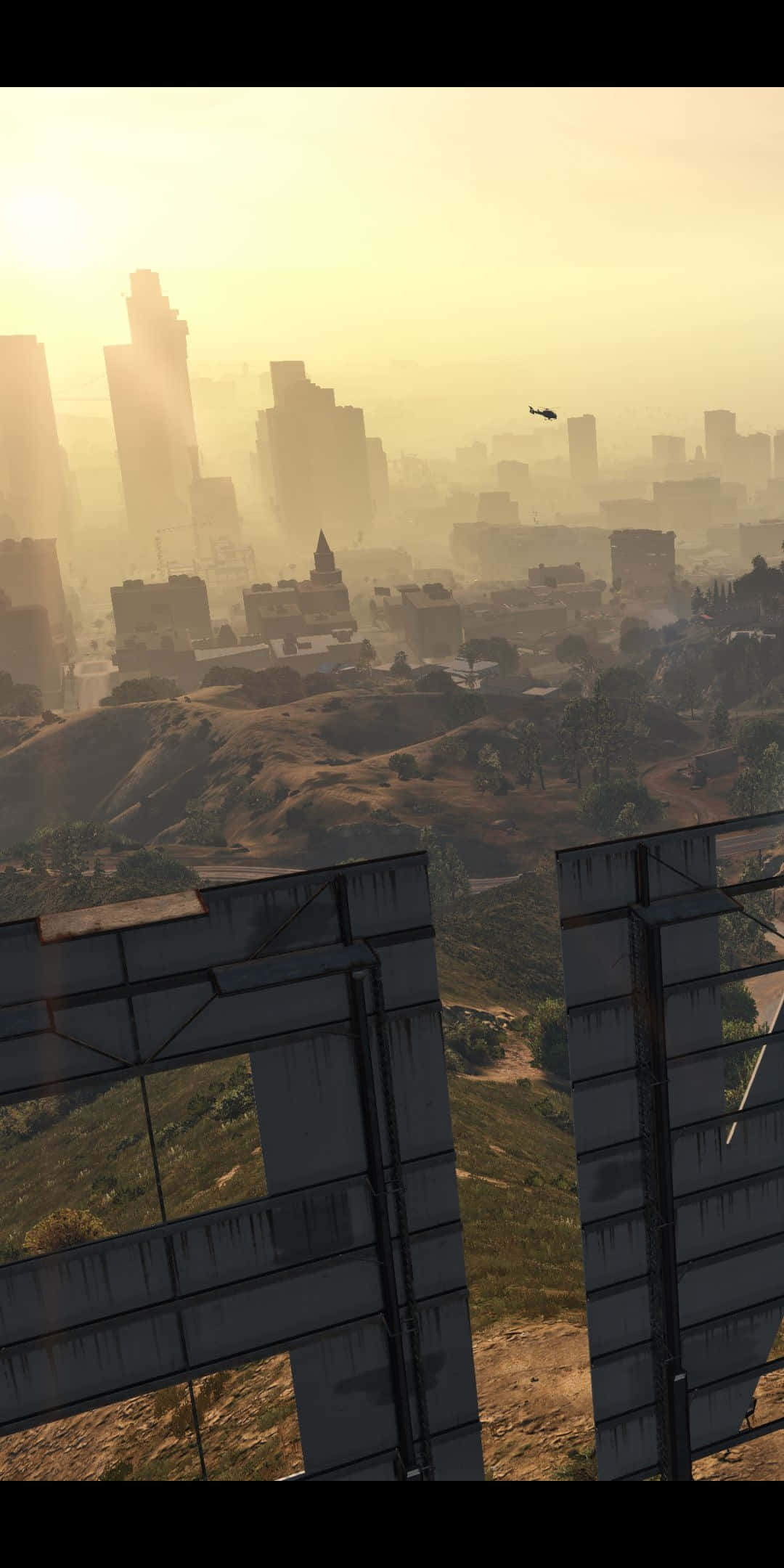 Pixel 3 Grand Theft Auto V 桌布 壁紙 — 朦朧的金色日出沐浴著廣闊的城市景觀，高聳的摩天大樓和遠處的直升機飛越起伏的山丘。
