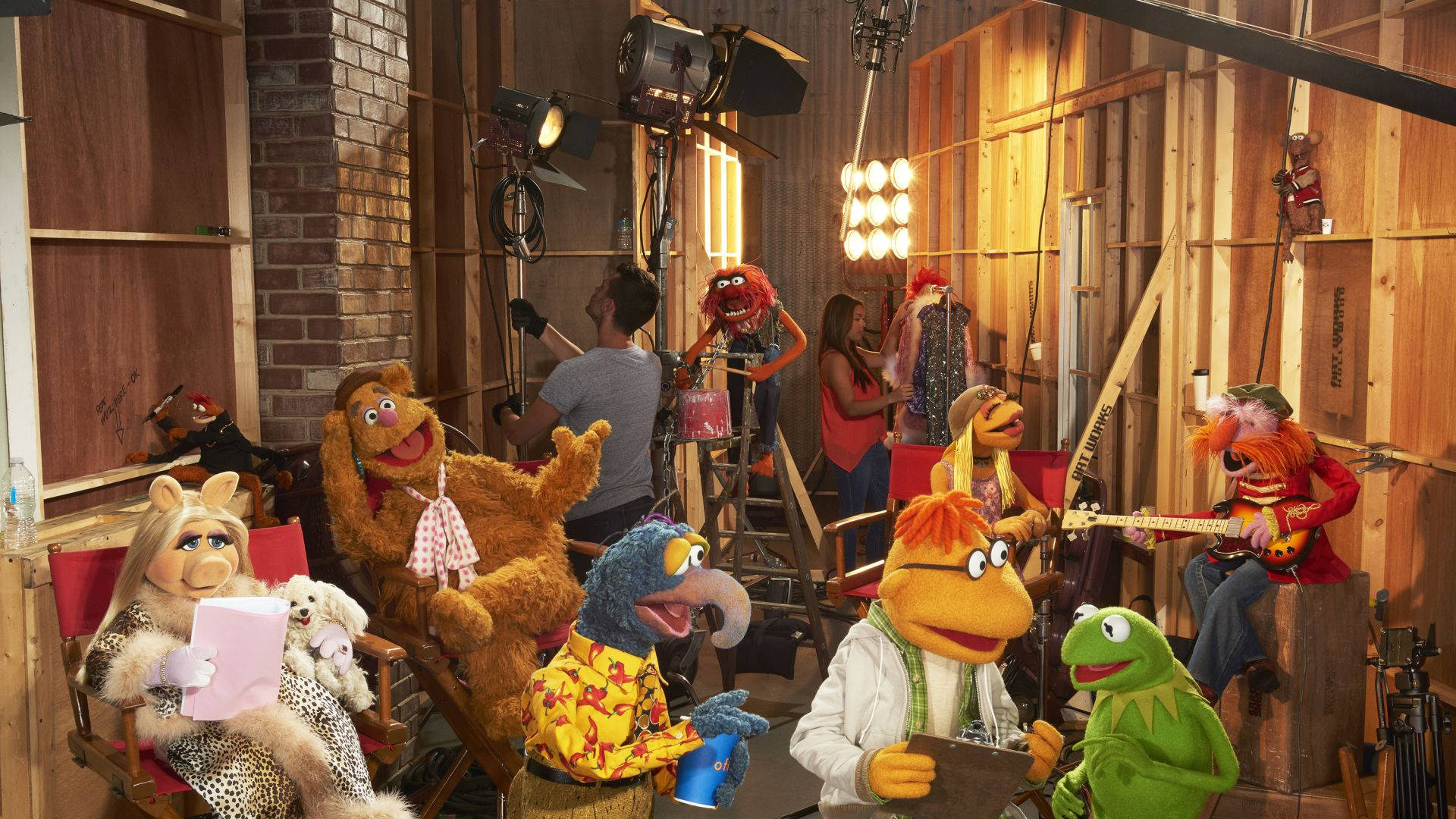 kermit 桌布 壁紙 — 木偶在質樸的木製工作室中，周圍有照明設備和工作人員。