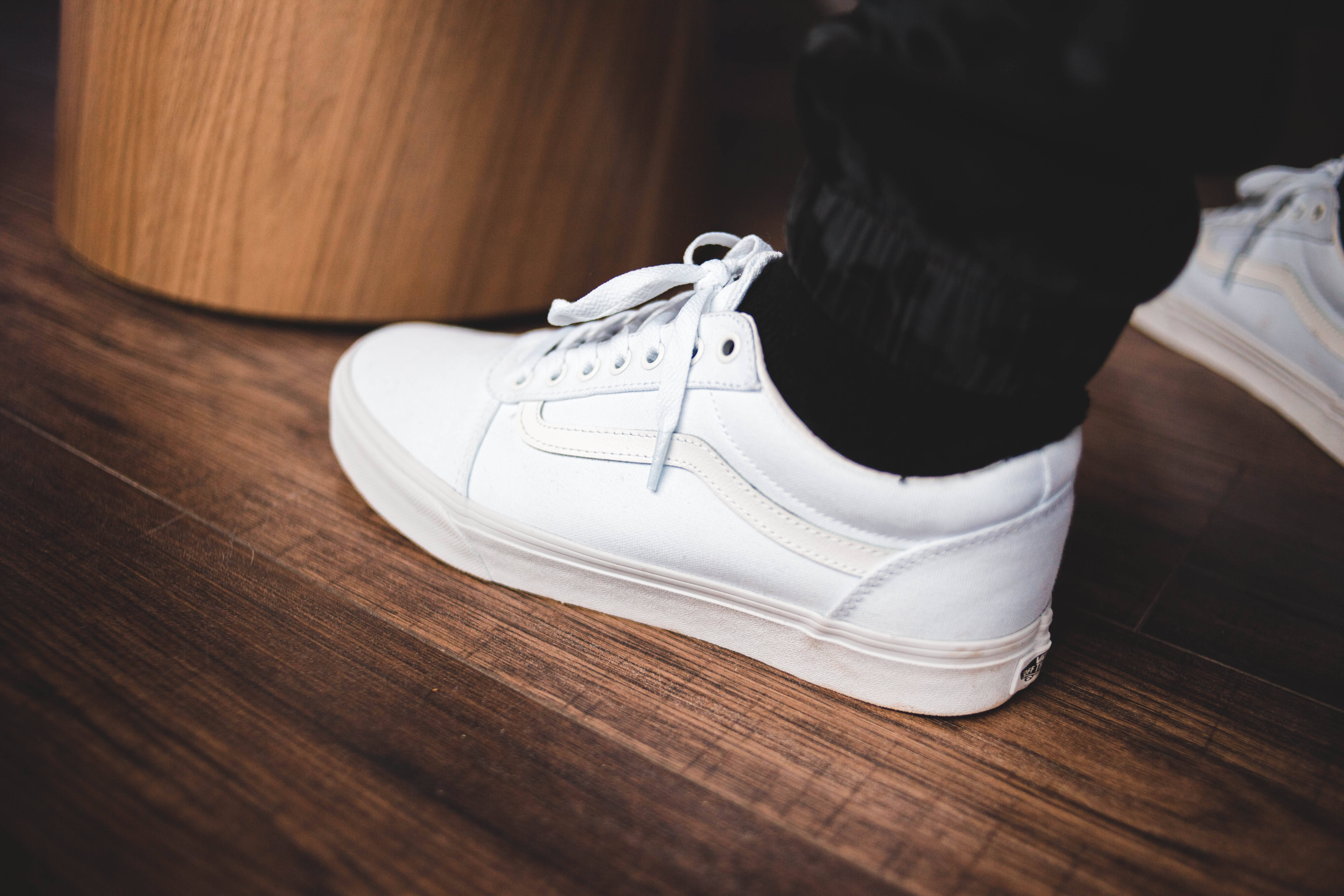 Sneaker 桌布 壁紙 — 木地板上一隻白色運動鞋搭配黑色襪子，旁邊有一個木凳的近距離特寫。