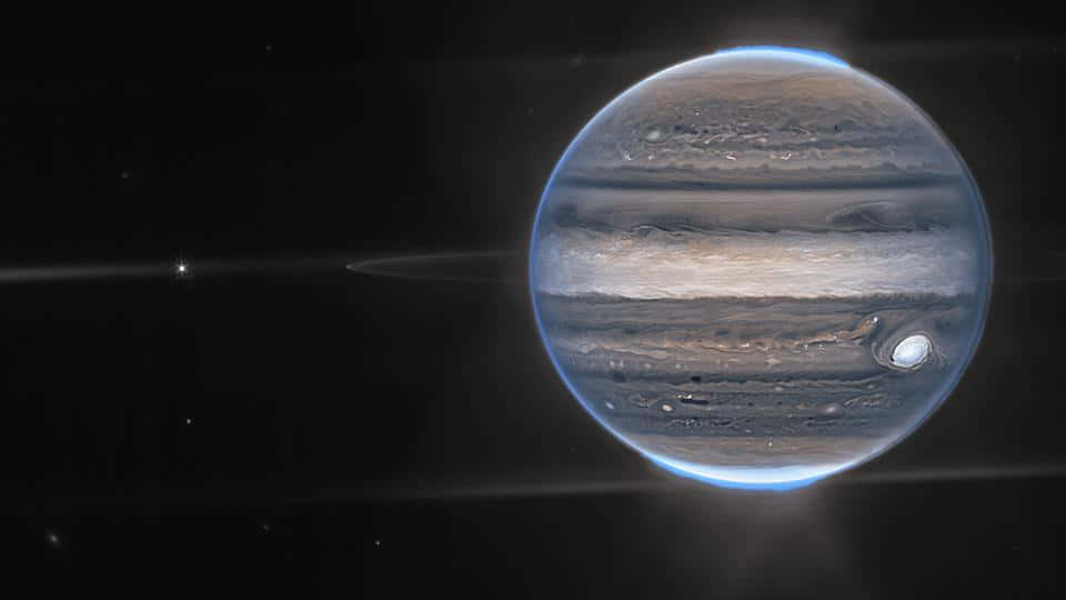 木星 桌布 壁紙 — 木星在太空中顯得巨大，帶有棕色、米色和白色雲層的旋轉帶，以及明亮的藍色大氣輝光。