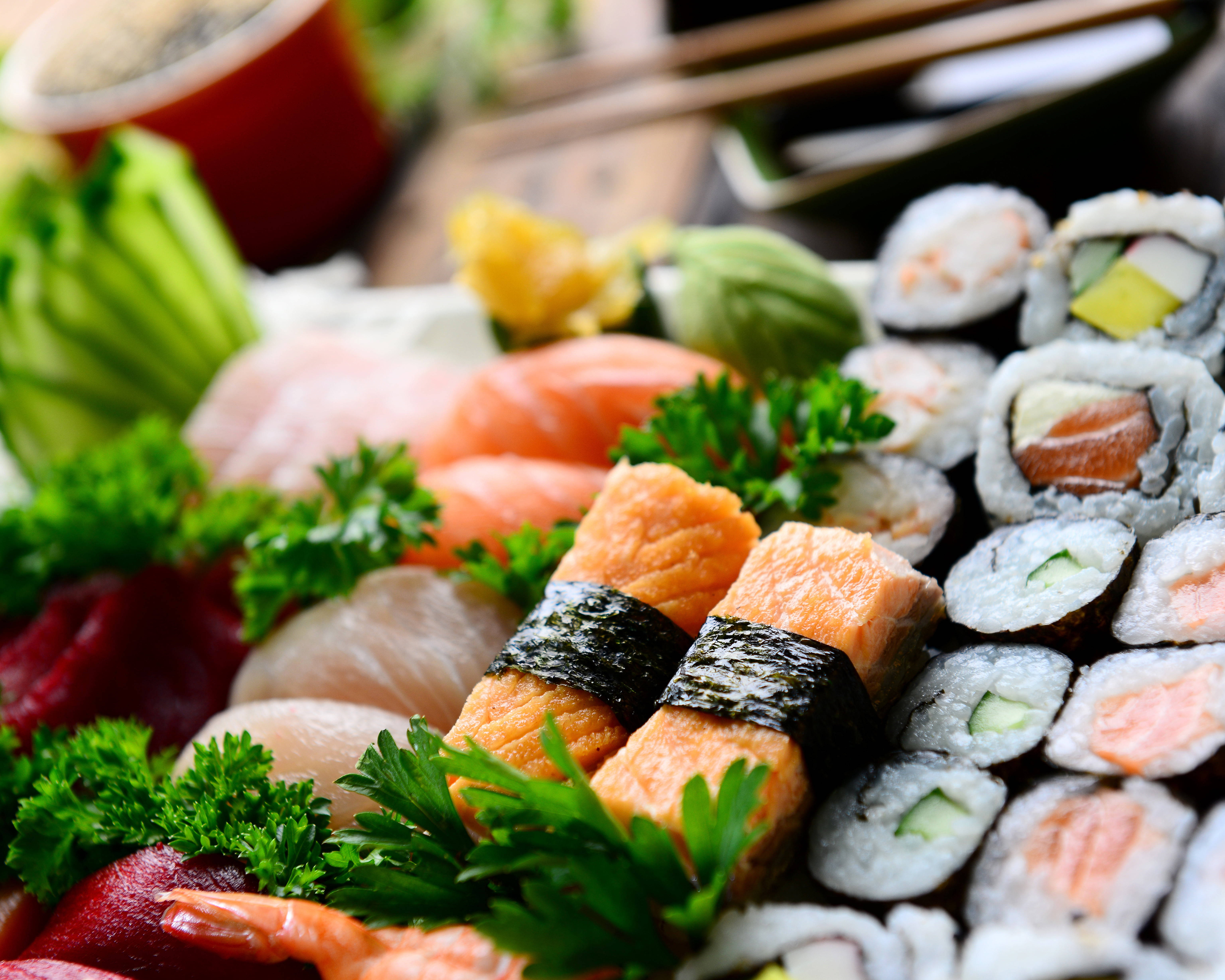 Sushi 桌布 壁紙 — 木桌上新鮮歐芹裝飾的各款壽司卷和刺身的鮮豔特寫。