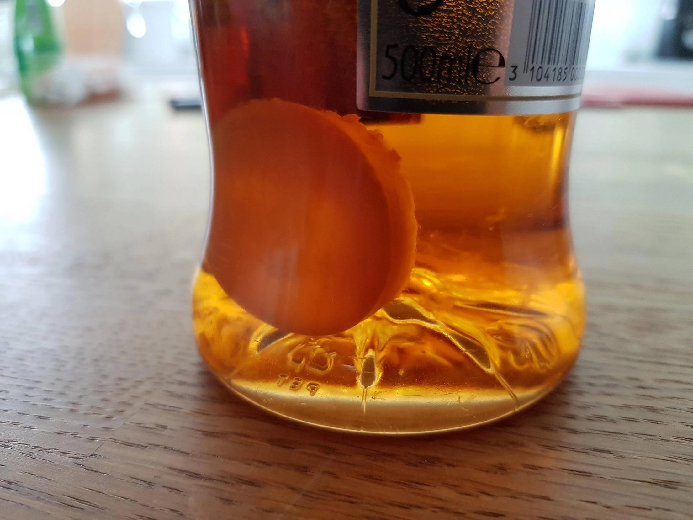 Drink 桌布 壁紙 — 木桌上琥珀色液體瓶的特寫，內有漂浮的橙片。