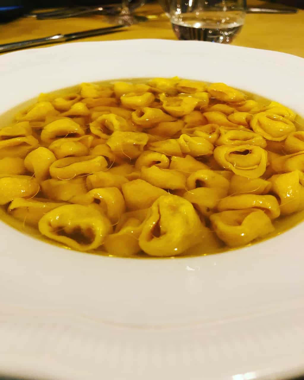 Pasta 桌布 壁紙 — 木桌上白色碗中漂浮在金黃色濃湯中的義大利餃子特寫。