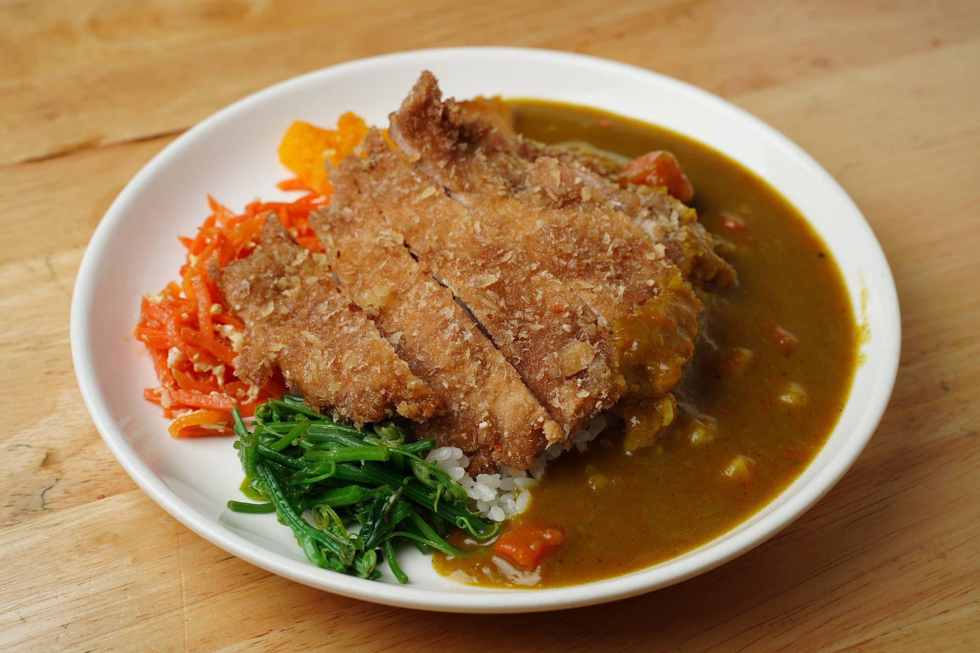 Food Photography 桌布 壁紙 — 木桌上的一盤脆皮咖哩吉列豬排飯，配有蘿蔔絲和菠菜。