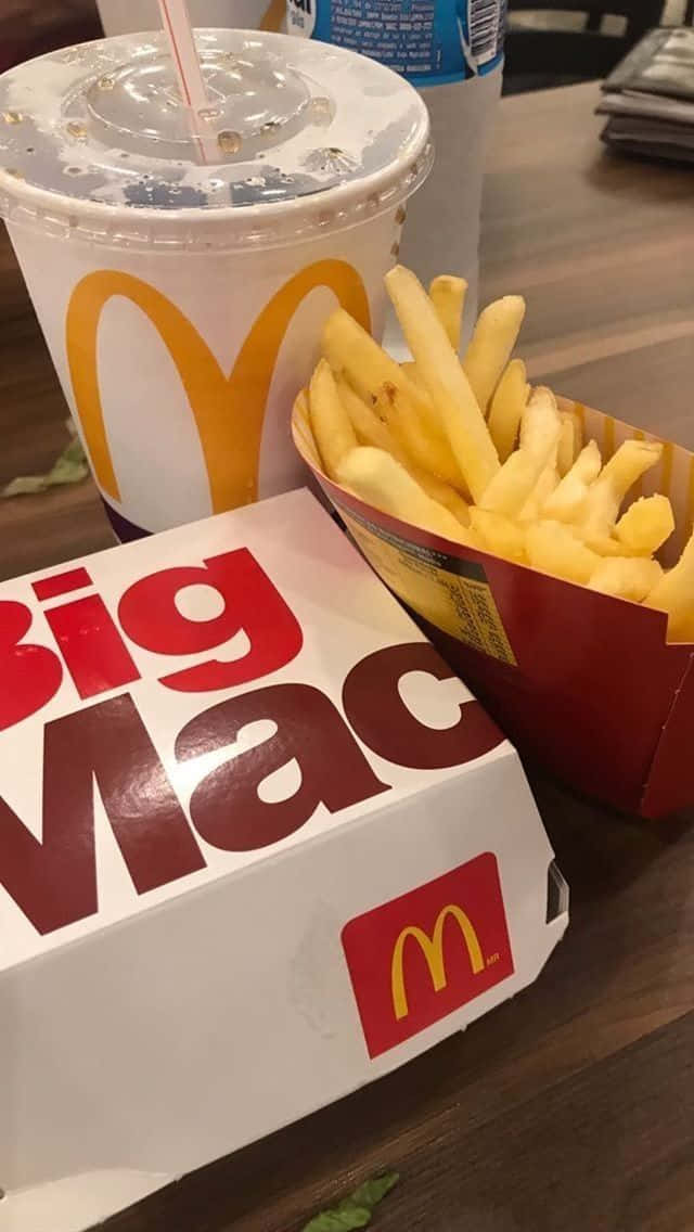 Soda 桌布 壁紙 — 木桌上麥當勞大麥克盒和薯條旁邊放著飲料杯的特寫。