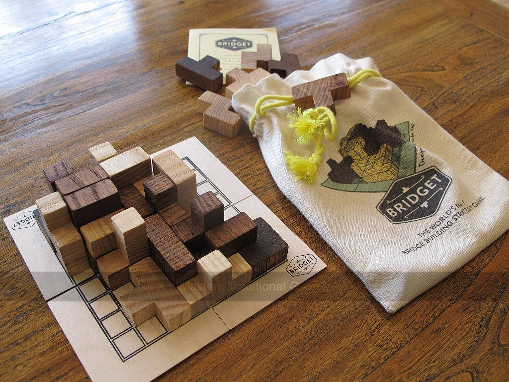 game 桌布 壁紙 — 木橋建造拼圖遊戲棋子排列在網格板上，旁邊是一個有品牌的帆布袋，放在溫暖的木桌上。