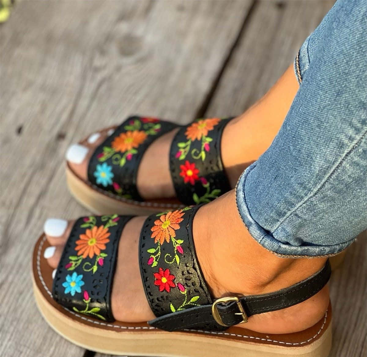 Sandals 桌布 壁紙 — 木甲板上彩色花卉刺繡涼鞋配捲邊牛仔褲的特寫。