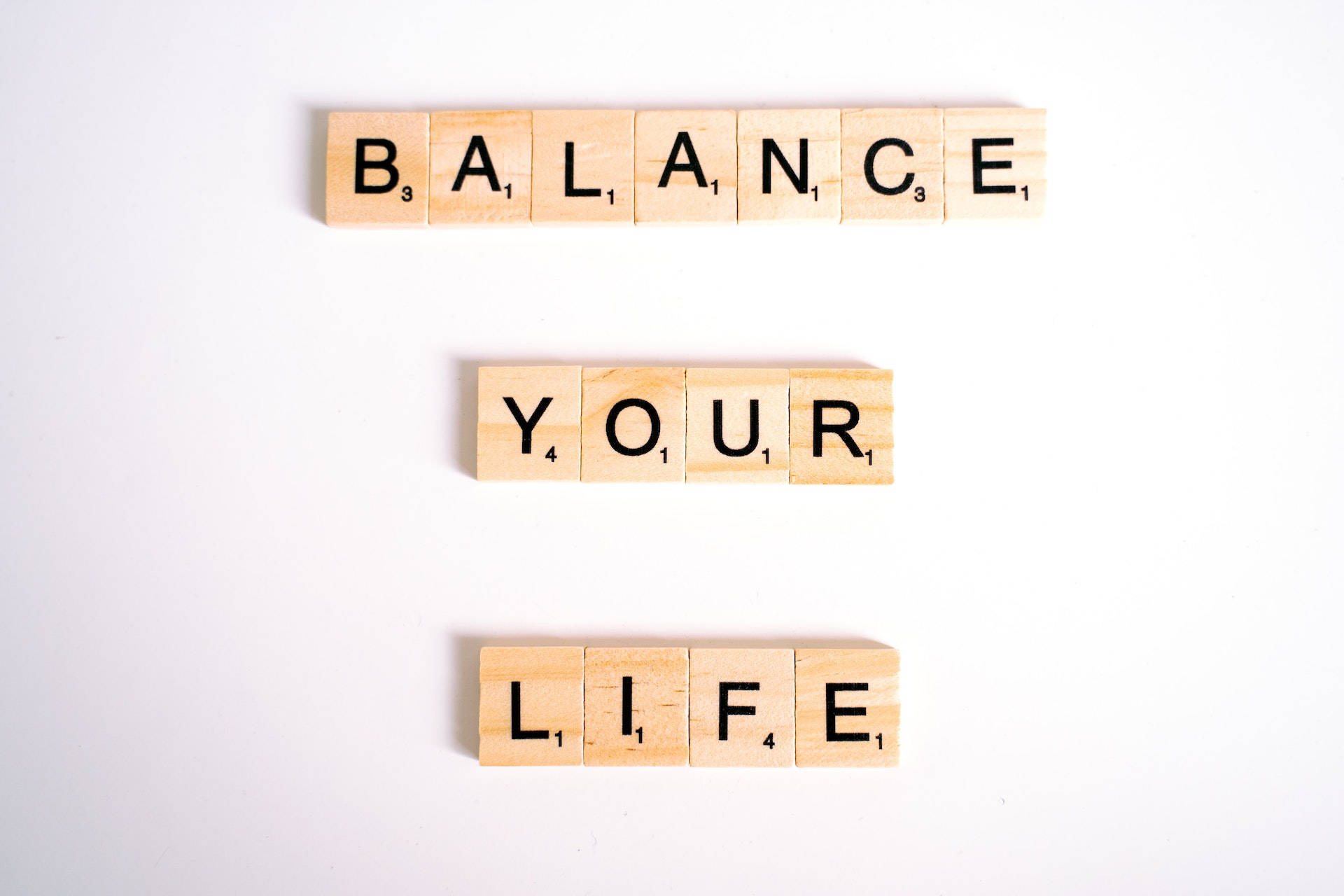 勵志語錄 桌布 壁紙 — 木製 Scrabble 字母牌在純白背景上拼出三行 'BALANCE YOUR LIFE'。