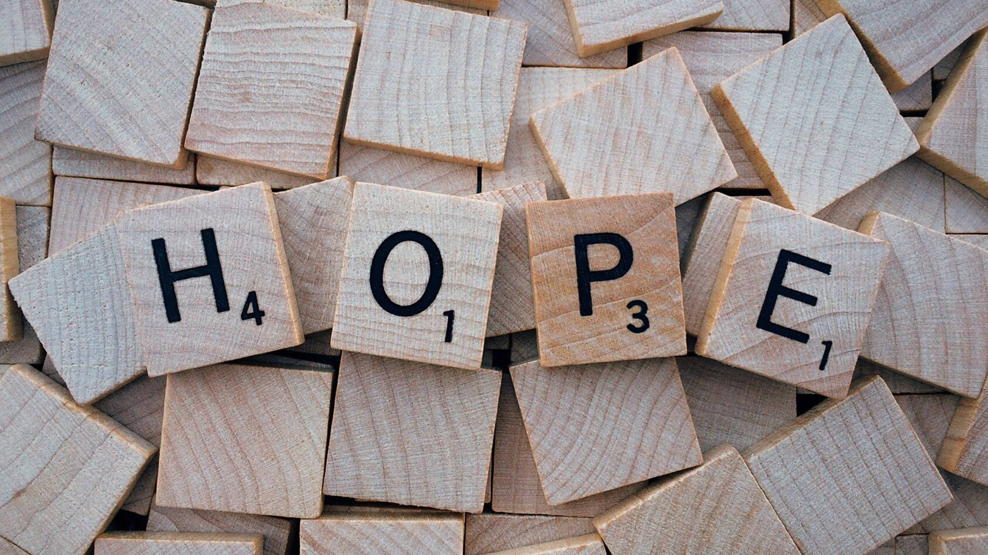 高清 桌布 壁紙 — 木製 Scrabble 字母牌拼出「希望」一詞，散落在一堆空白字母牌上，帶有天然木紋。