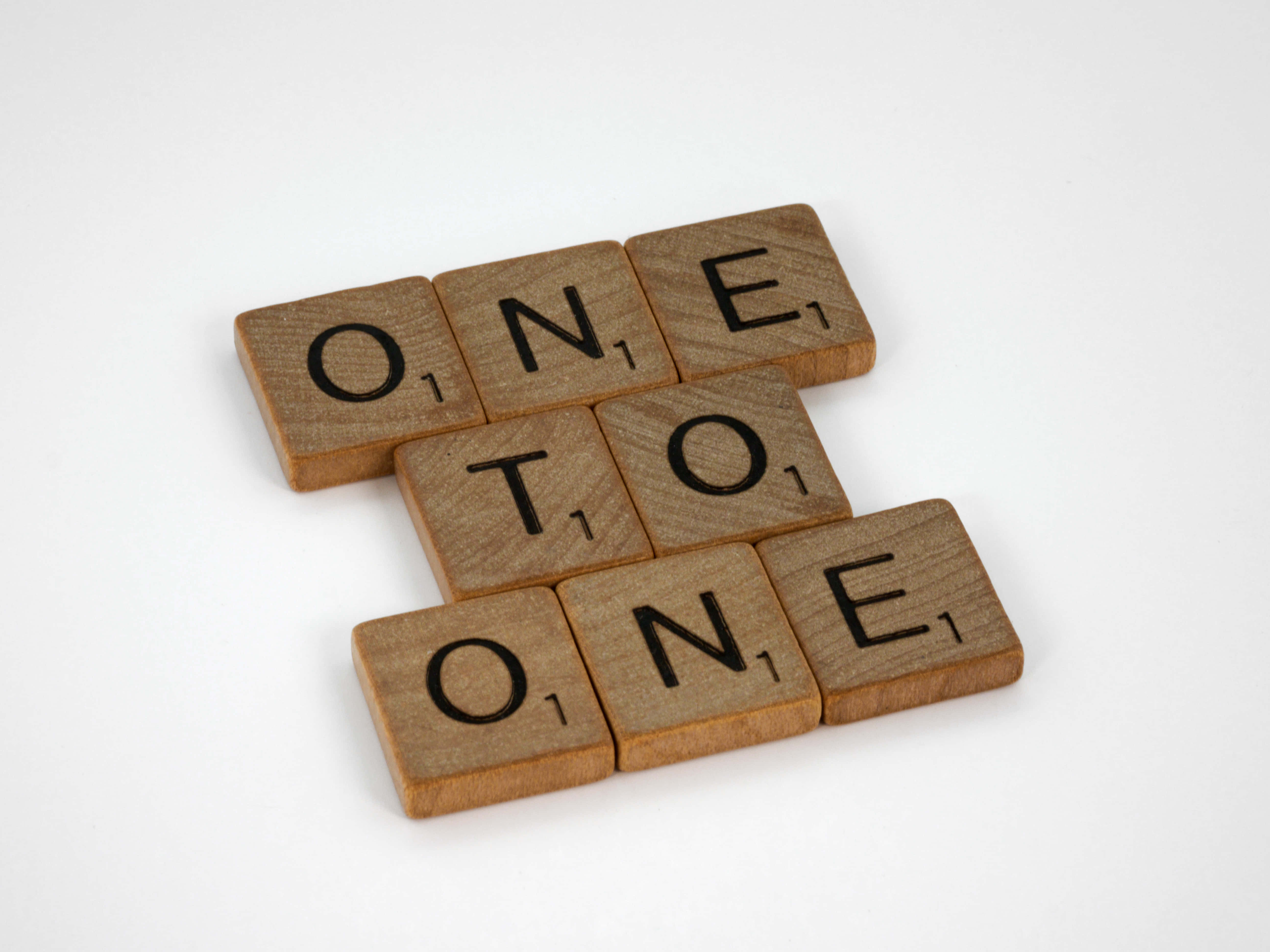 木紋 桌布 壁紙 — 木製 Scrabble 字母牌拼出 'ONE TO ONE'，以交錯排列方式放置在純白背景上。