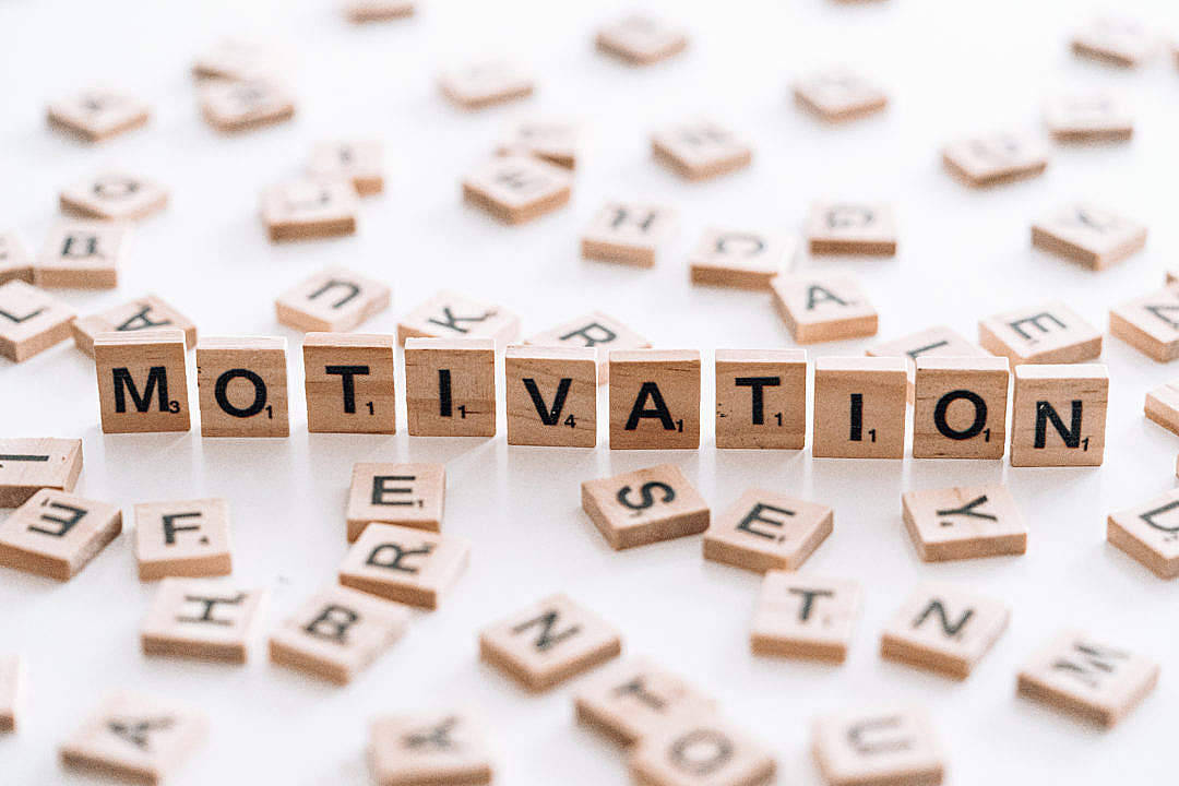 Motivational Quotes 桌布 壁紙 — 木製 Scrabble 字母磚在明亮的白色背景上拼出動力，並散落著字母。