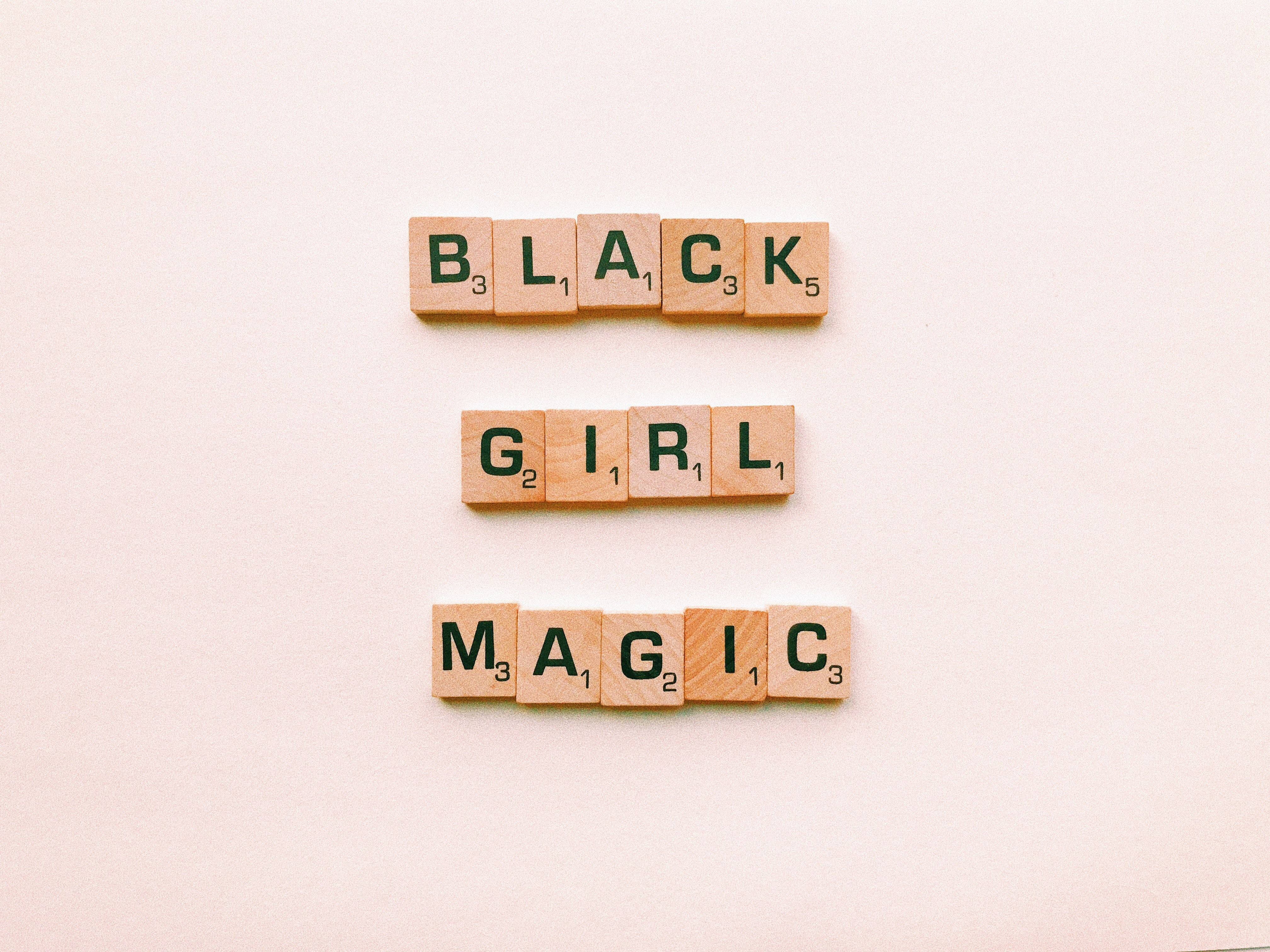 Black Girl 桌布 壁紙 — 木製 Scrabble 字母磚在柔軟的米色背景上以粗體綠色字母拼出「BLACK GIRL MAGIC」。